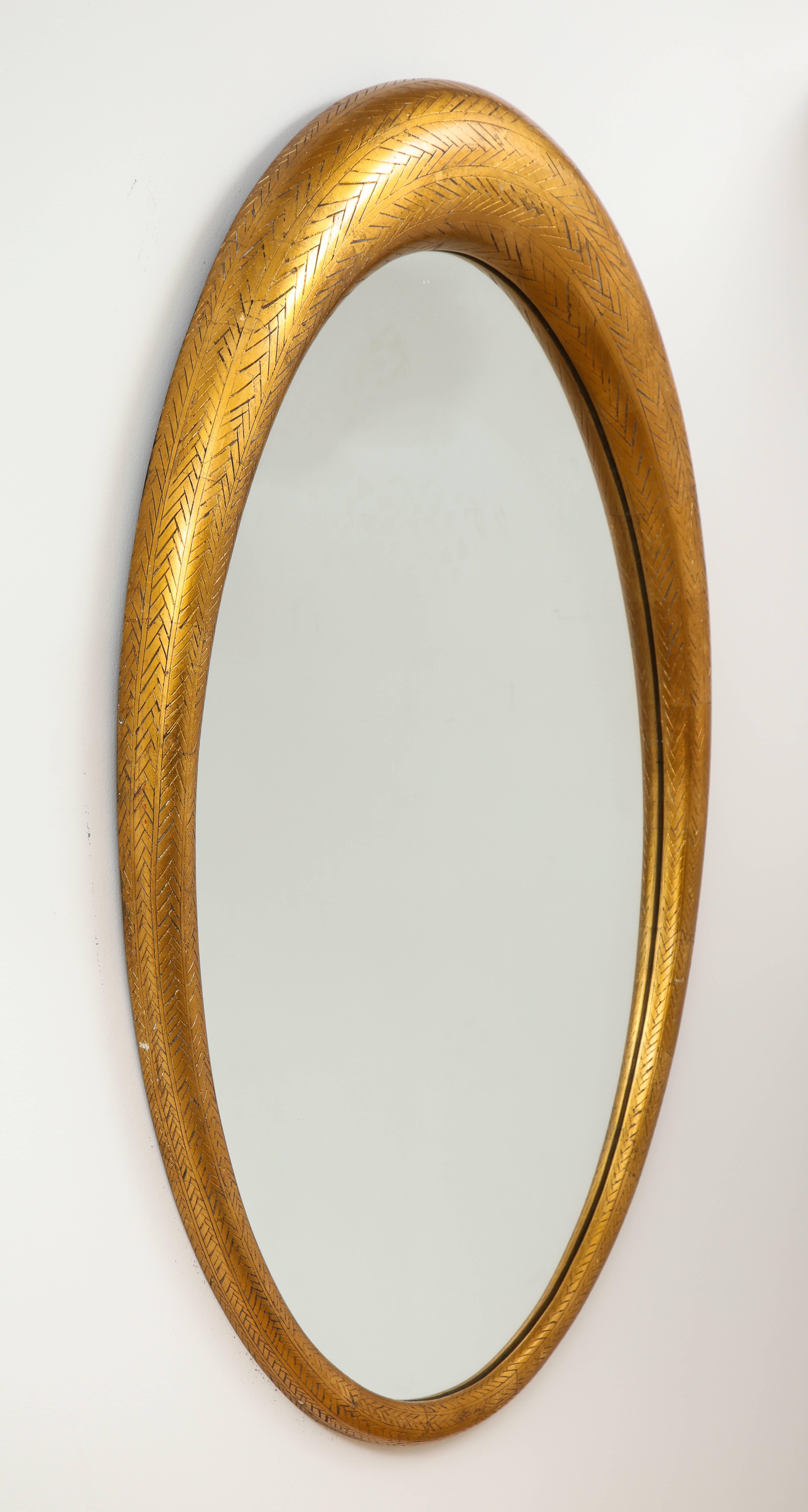 A gilded wood oval modernist mirror in graduated form with cross-hatch carving. 
American circa, 1950
Size: 45