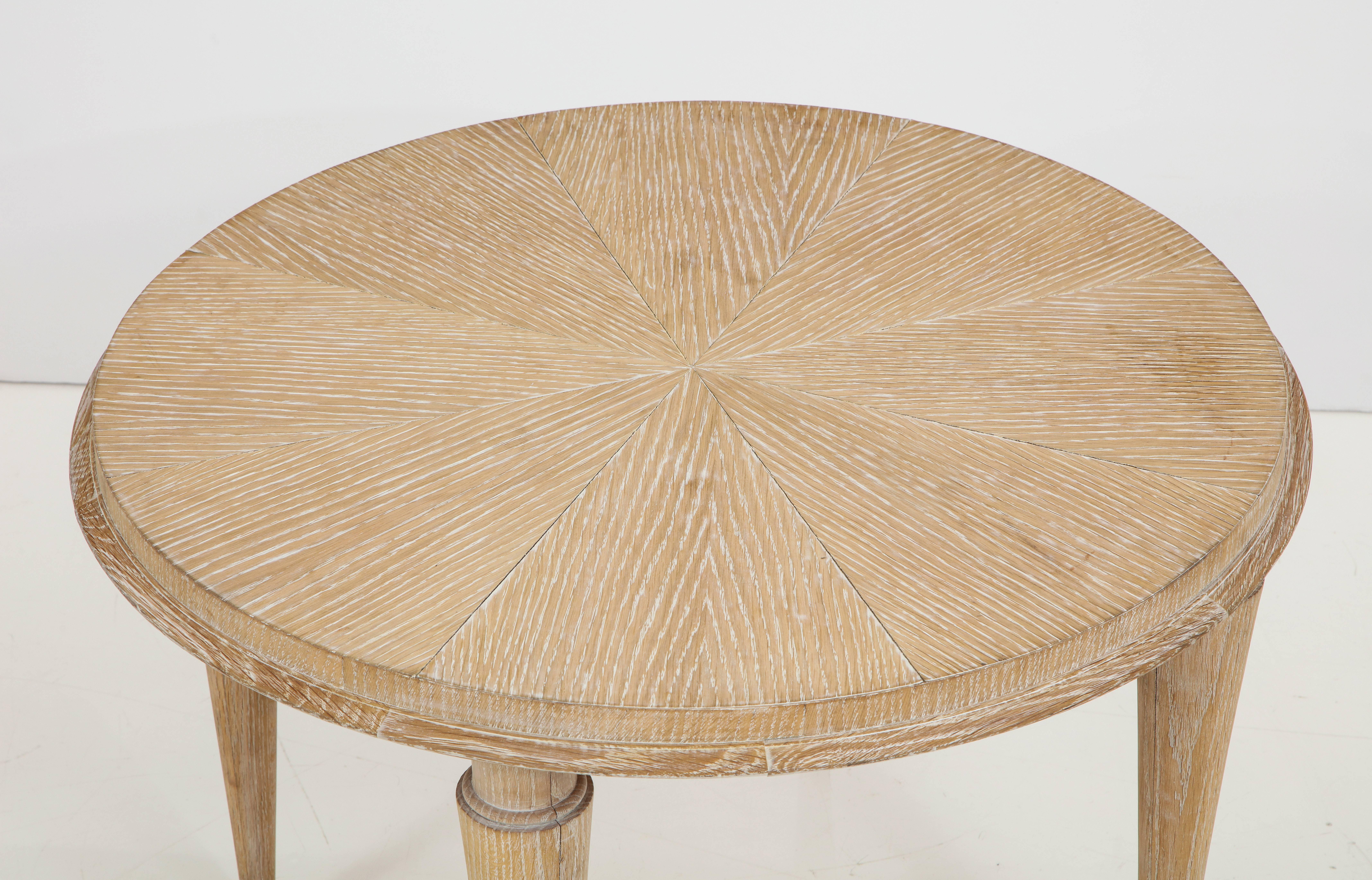 A French cerused oak round cocktail or side table raised on tapered legs with brass sabots. 
France, circa 1950 
Size: 29