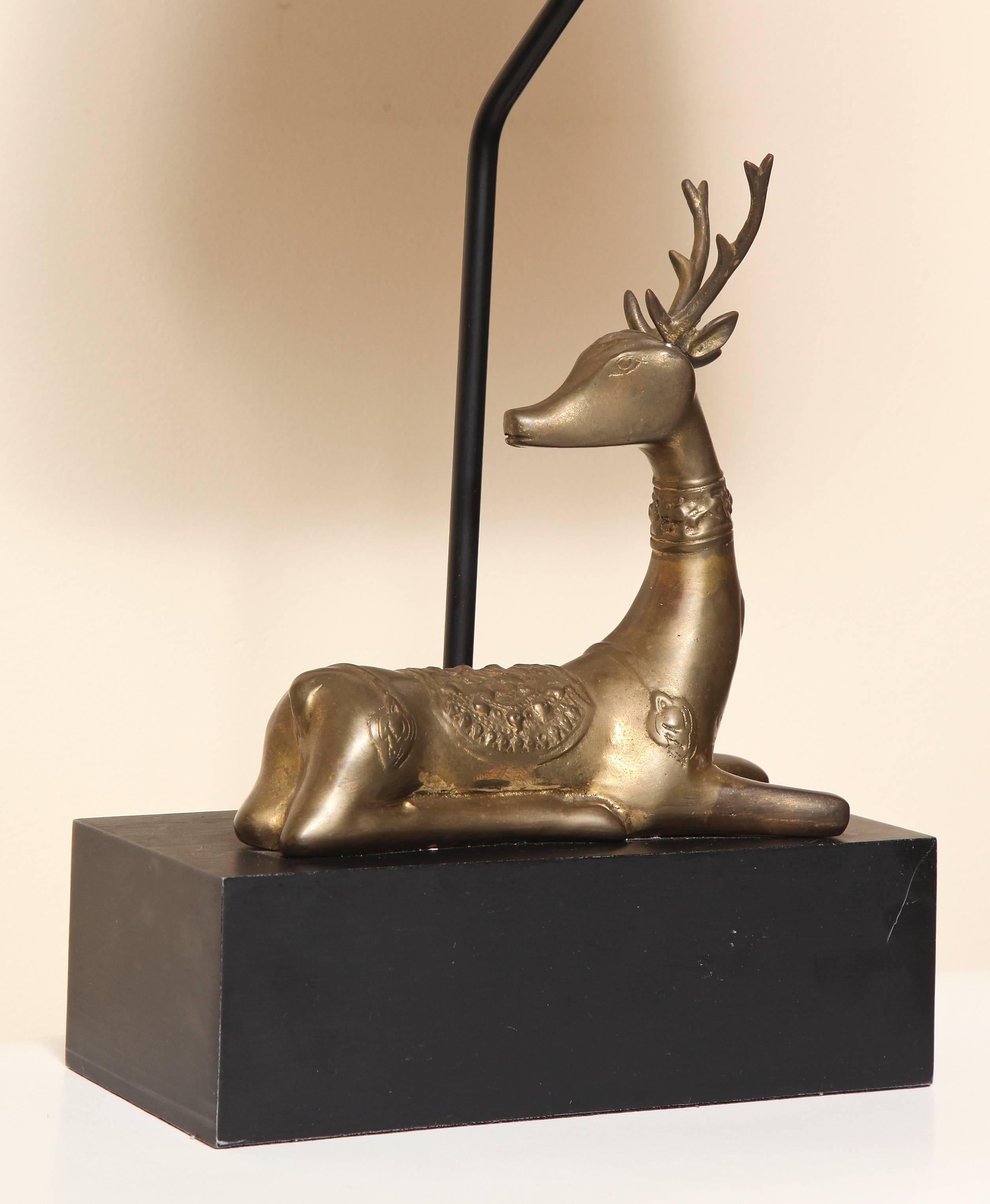 A brass deer mounted table lamp on a rectangular block wood plinth with painted ball finial. Made by Chapman, with label, dated 1977.