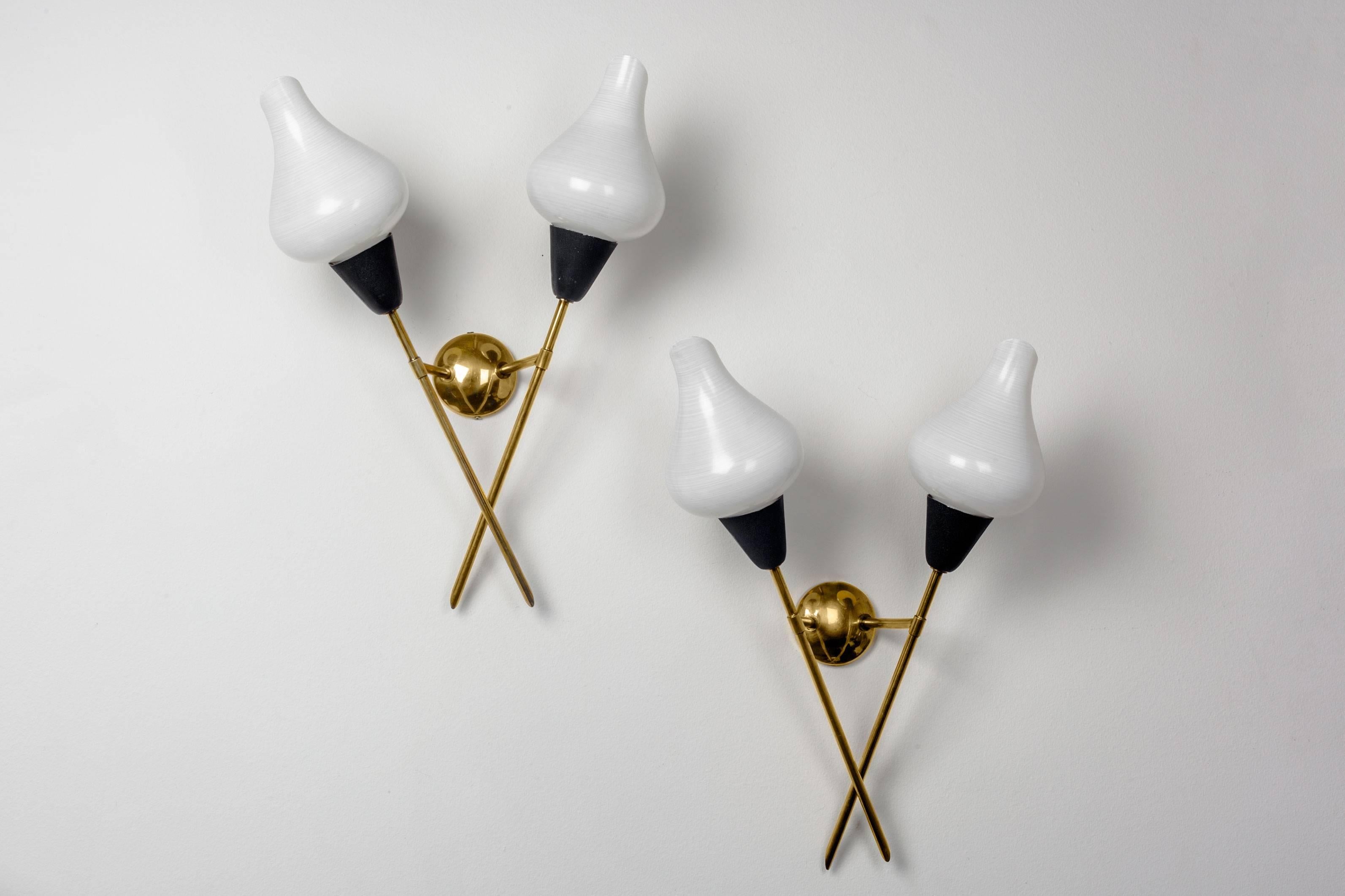 Mid-century French sconces by Arlus. Thin, crossed brass arms that end in opaline shades. These white milk glass shades have a subtile retticello effect, and a lovely shape reminiscent of a flower like the Calla Lily. Made in post-war France in the