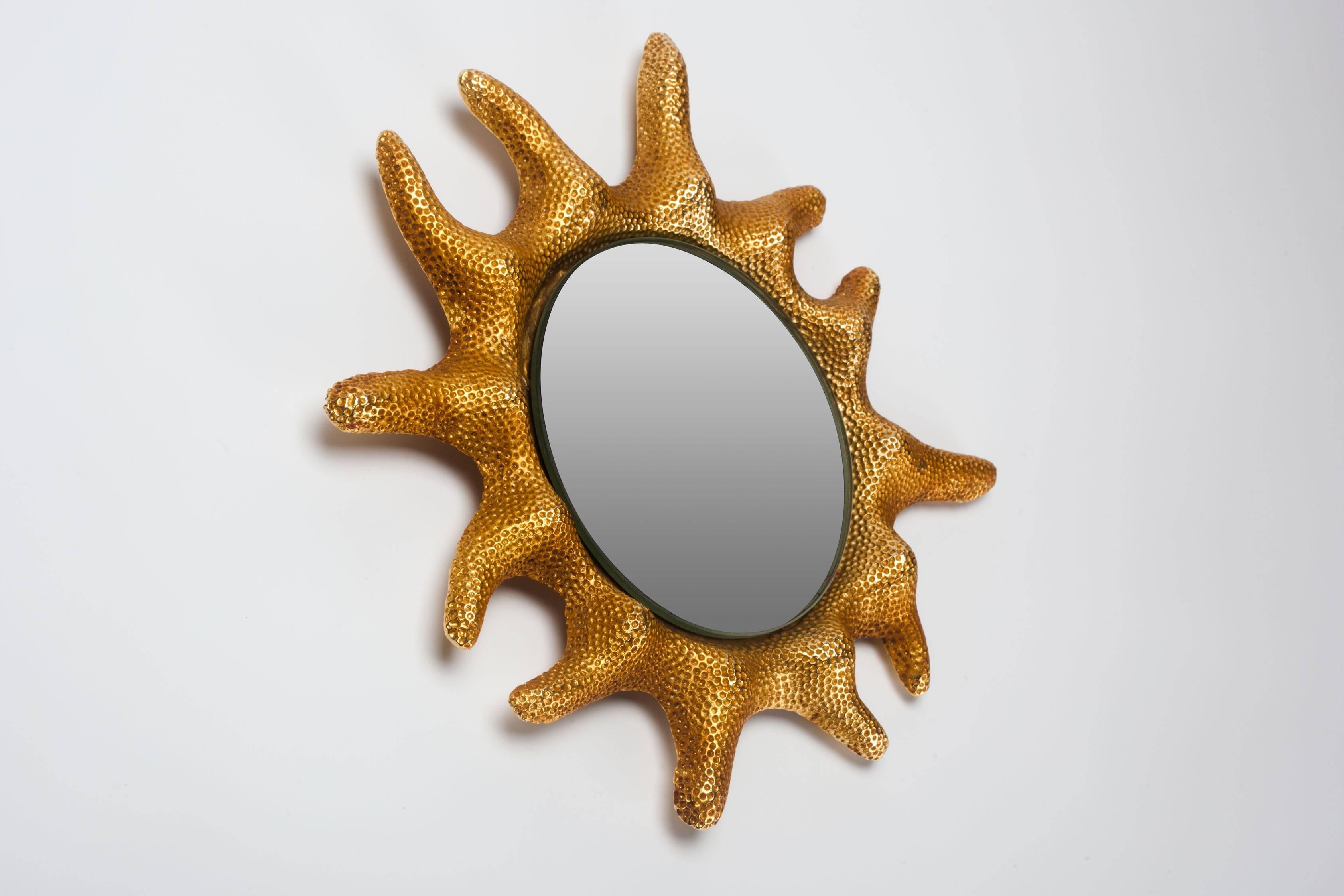 Round wall mirror framed in gilt bronze, made in France in 1995 and designed by Stéphane Galerneau for Fondica. 

The frame's multi-directional appendages evoke the sun, resembling rays of light or licks of flame, while the fine texture of the