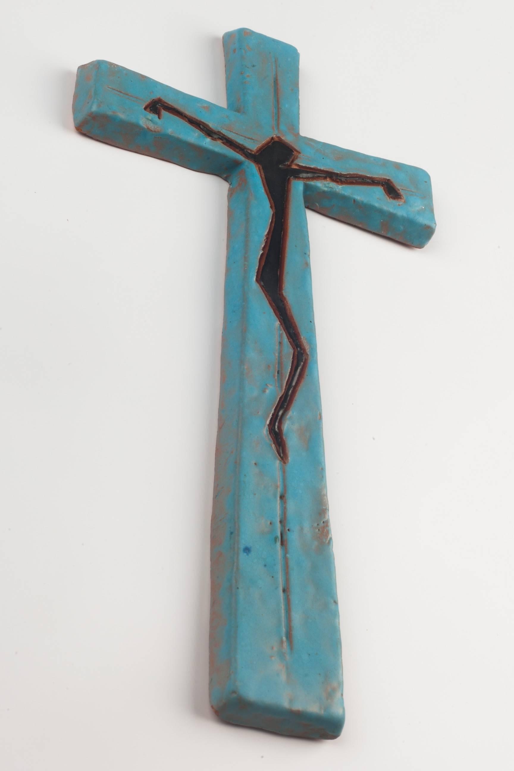 Over eight inch tall wall crucifix in ceramic, made in Belgium in the 1970s.
Black Christ figure outlined in brown over a sky blue cross. Christ figure drawn in straight lines and angles.

This piece is part of a 69 piece ceramic crucifix