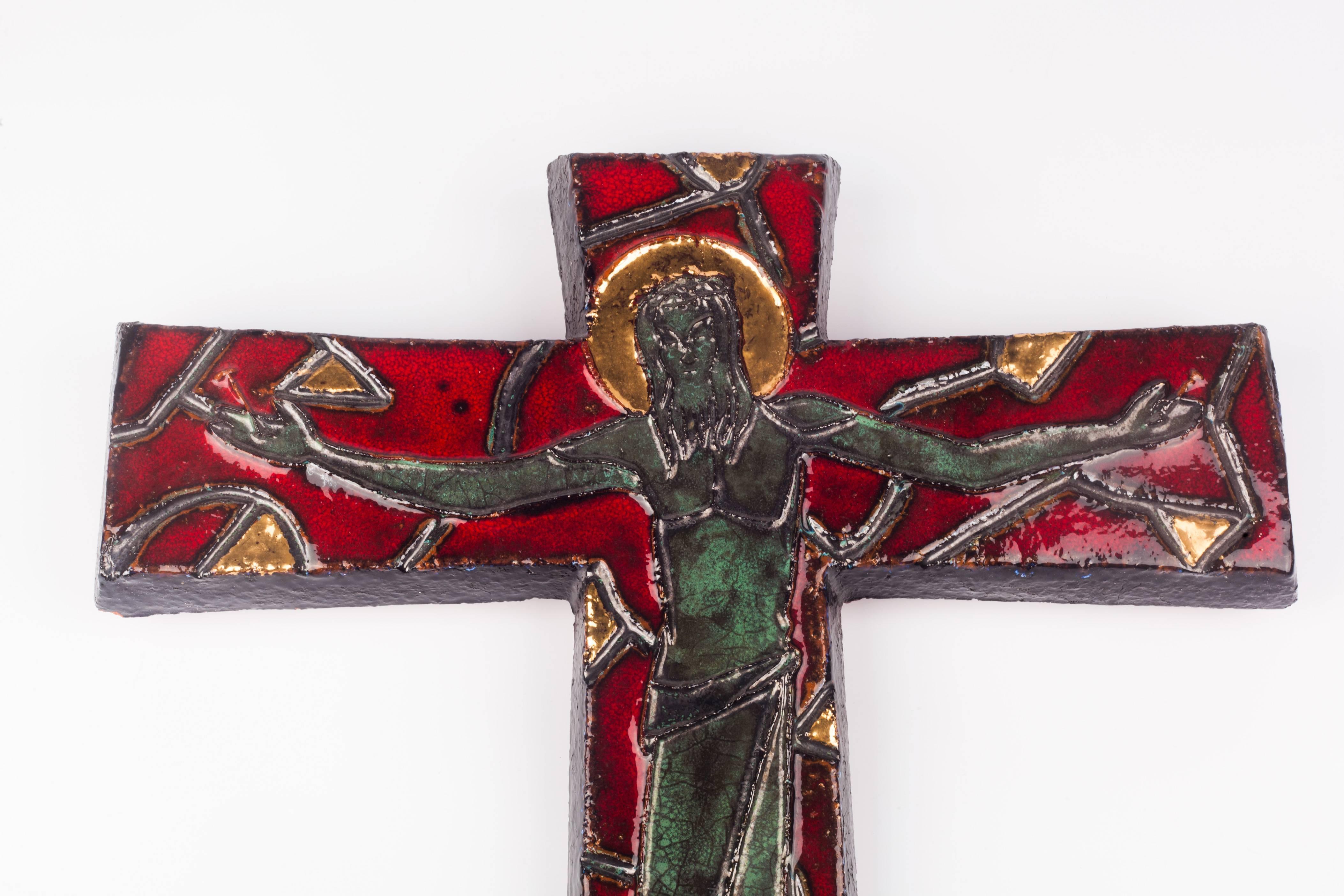 

Large, 16 inch tall wall crucifix in ceramic, made in Belgium in the 1980s.
Glossy marine green and grey iridescent christ on a deep red cross with stylized green-grey details resembling thorns. Gilt details throughout as well as halo around