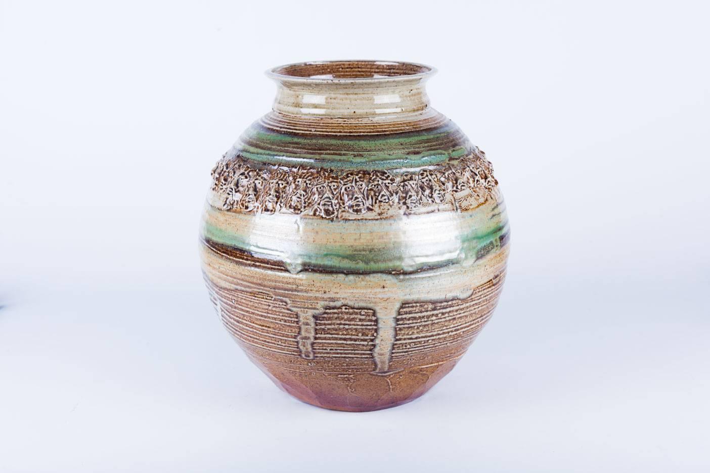 Large, handmade Raku pottery vessel by Phil Mundt (USA, 1933-2015), signed by the artist. Discreet and wisely chosen earthy color scheme with a subtle iridescence. Ring of Raku faces near top, and subtly faceted bottom. A meaningful and finely
