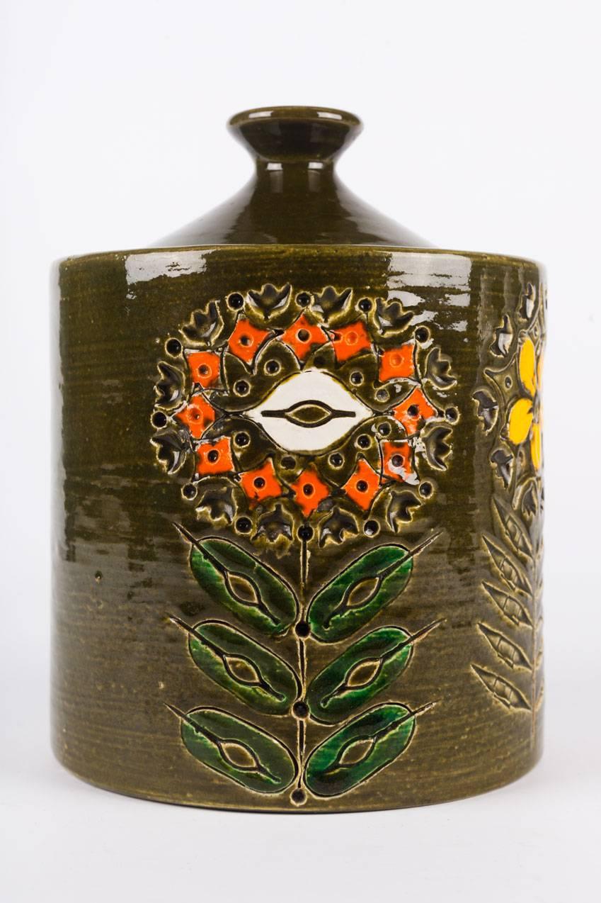 Large, lidded Bitossi cookie jar in glazed ceramic, made in Italy in the 1950s. Dark green with orange and yellow wild flower motif, a handmade organic folk design carved on one side.
