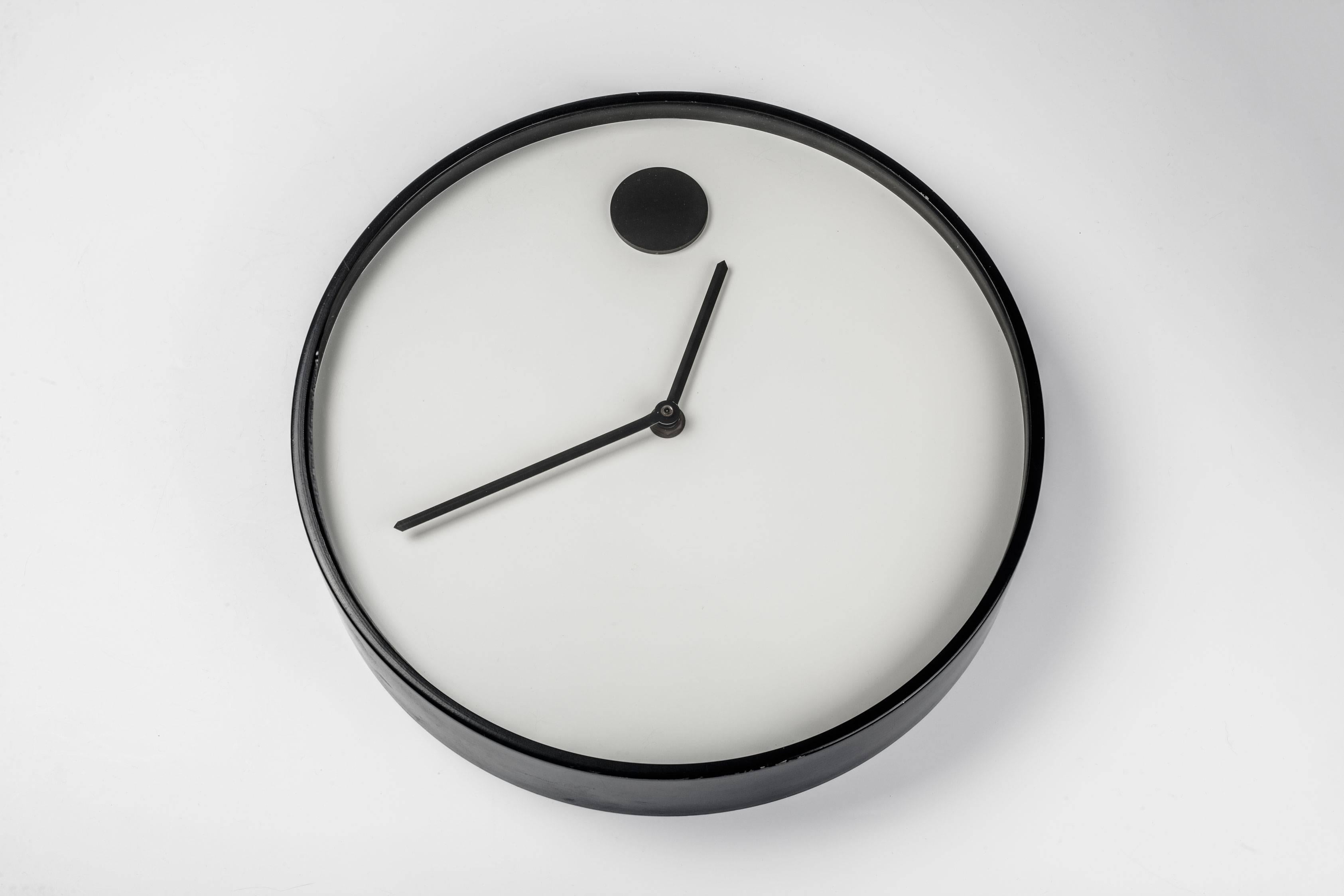 Black and white wall clock, part of the MoMA design collection, 1970. Designed by Nathan George Horwitt for Howard Miller. Metal lacquered case and glass front. A wall clock version of Horwitt's previous watch design for Movado. 

Nathan George