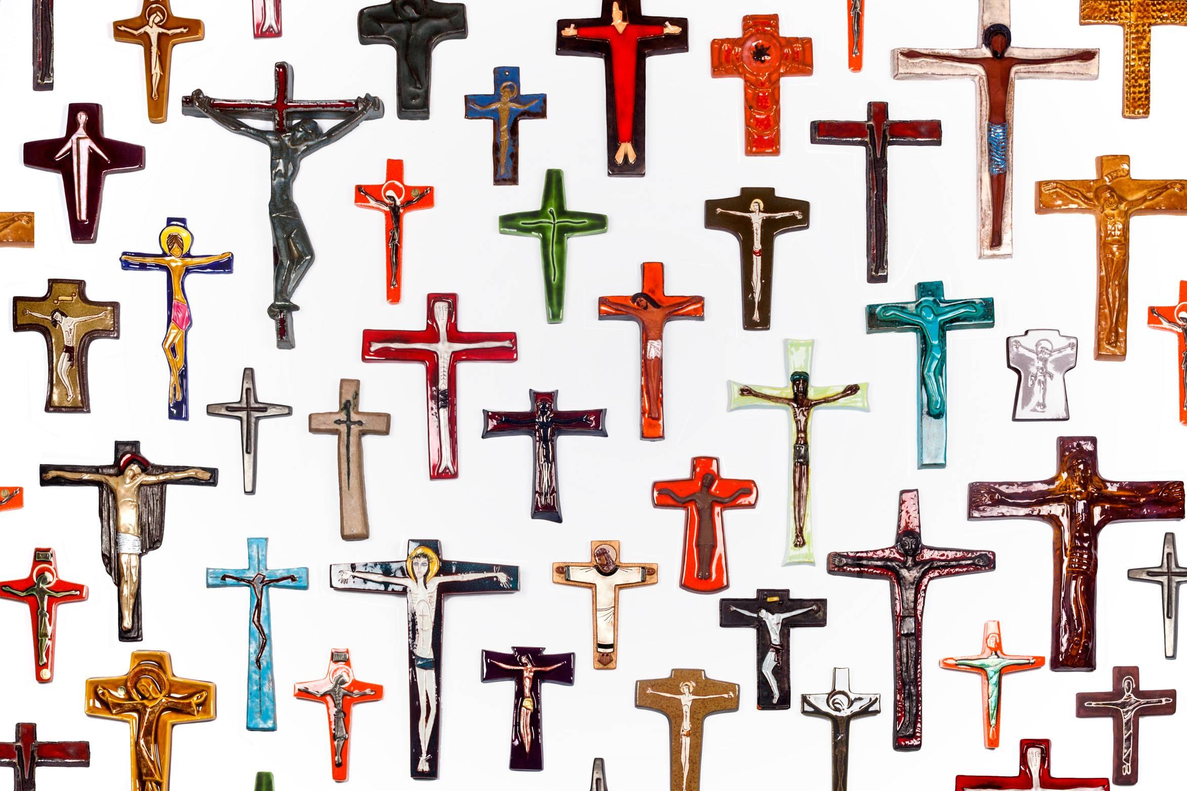 Ceramic wall cross, nearly eight inches tall, handmade in Belgium in the 1970s. Hand-painted in orange and black with white contours and finished in a high-gloss glaze. 

This piece is part of a 69-piece ceramic crucifix collection, all handmade