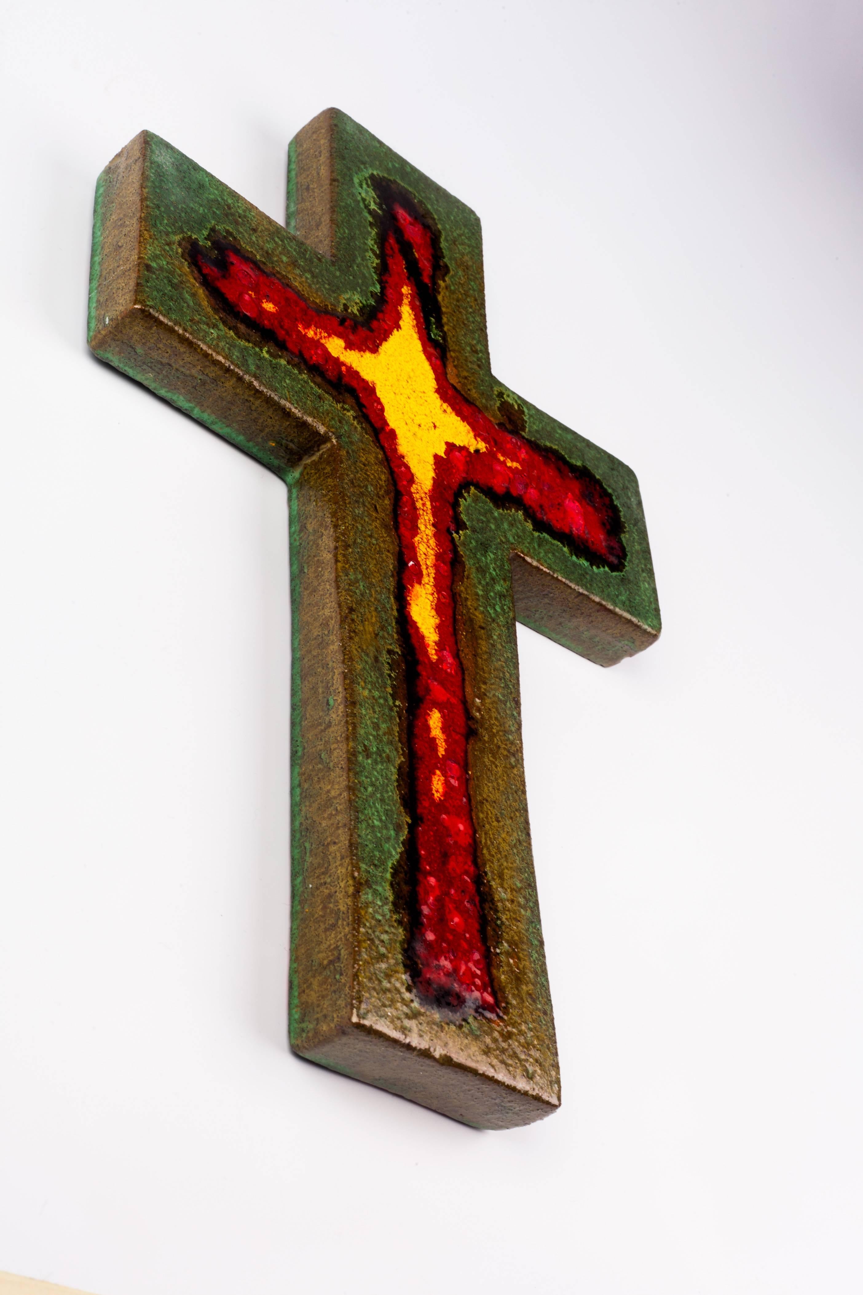 Eleven inch tall wall crucifix in ceramic, handmade in Belgium in the 1980s.
Glossy marine green cross with red and yellow interior cross shape. The color red has fat lava textured craters. 

A large piece with eye catching juxtaposition of