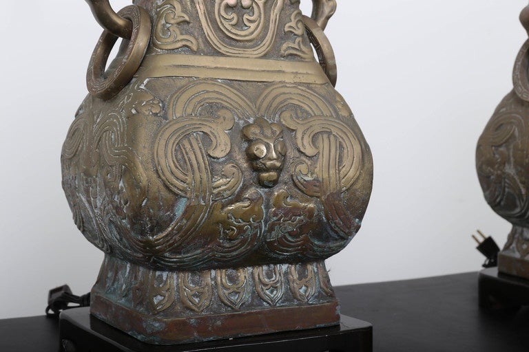 Impressive urn shape chinoiserie design bas relief lamps with mahogany wood caps and carved base.