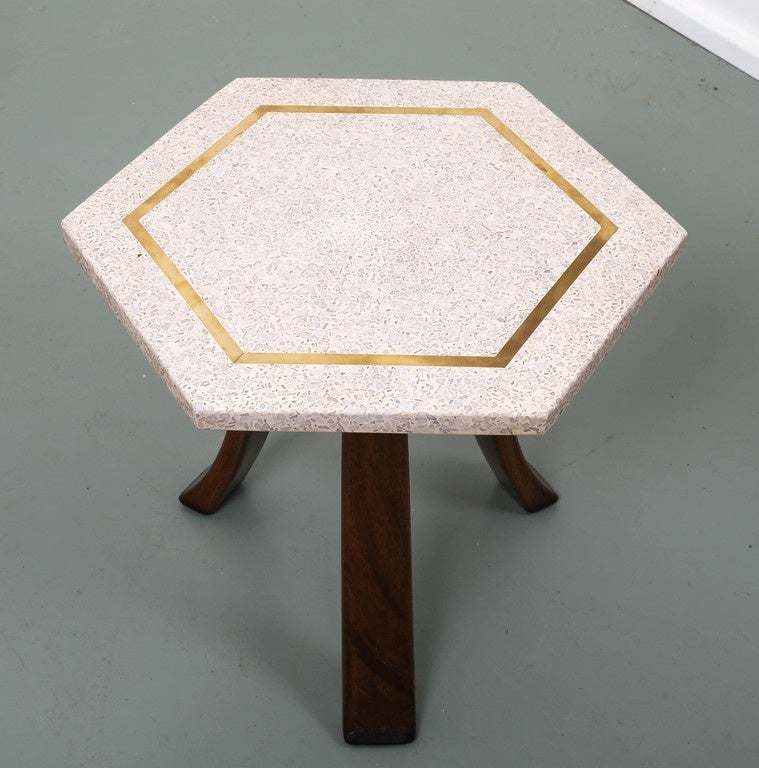 Elegant side table with terrazzo and brass inlaid hexagonal top, supported by three mahogany bent legs.