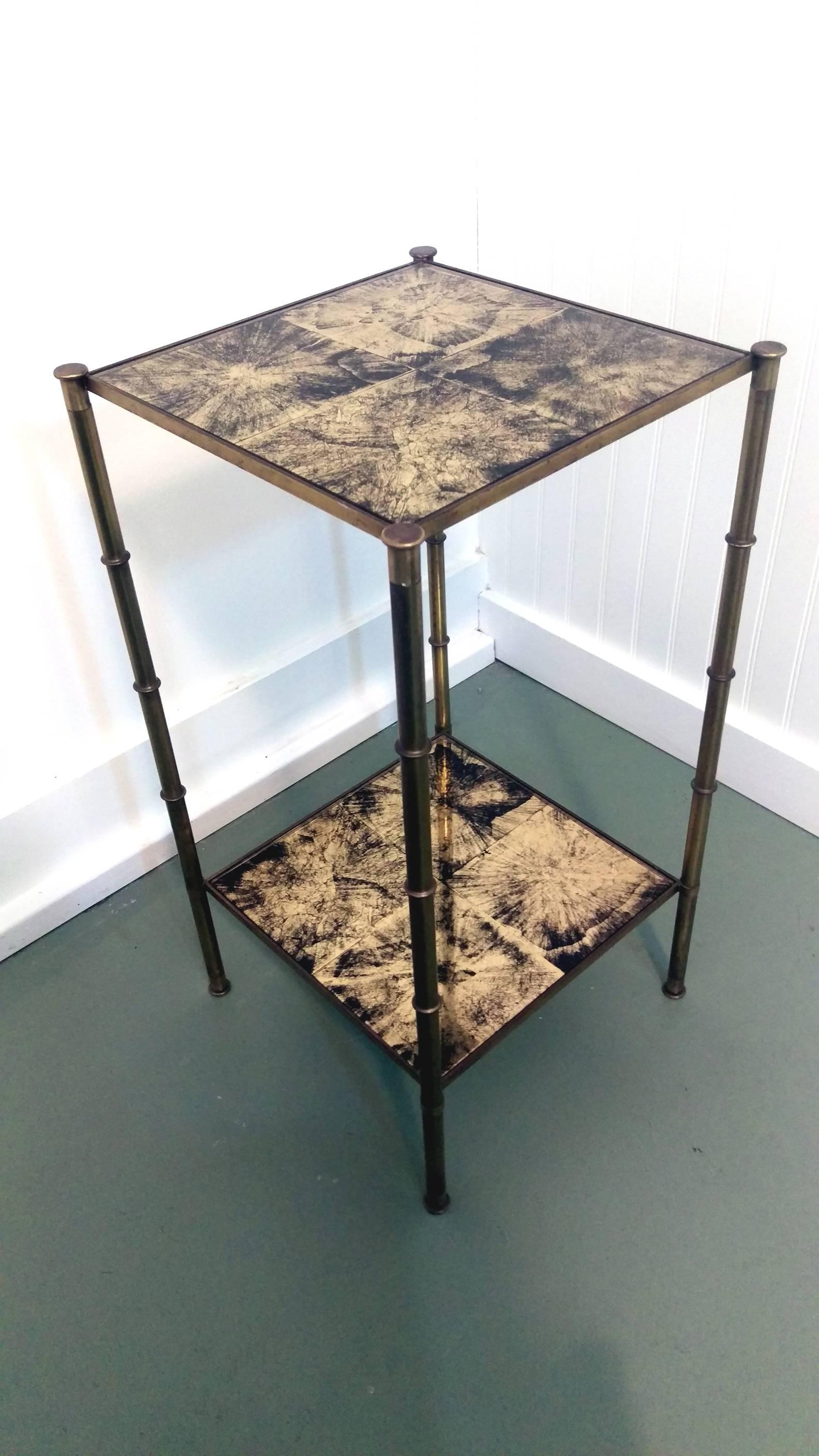A elegant French Baguès style faux bamboo brass side table, original patina brass frame complimented by gilt églomisé glass top and shelve, circa 1950s. There is a tiny chip on one the glass underside, but neither it shown on the surface, nor the