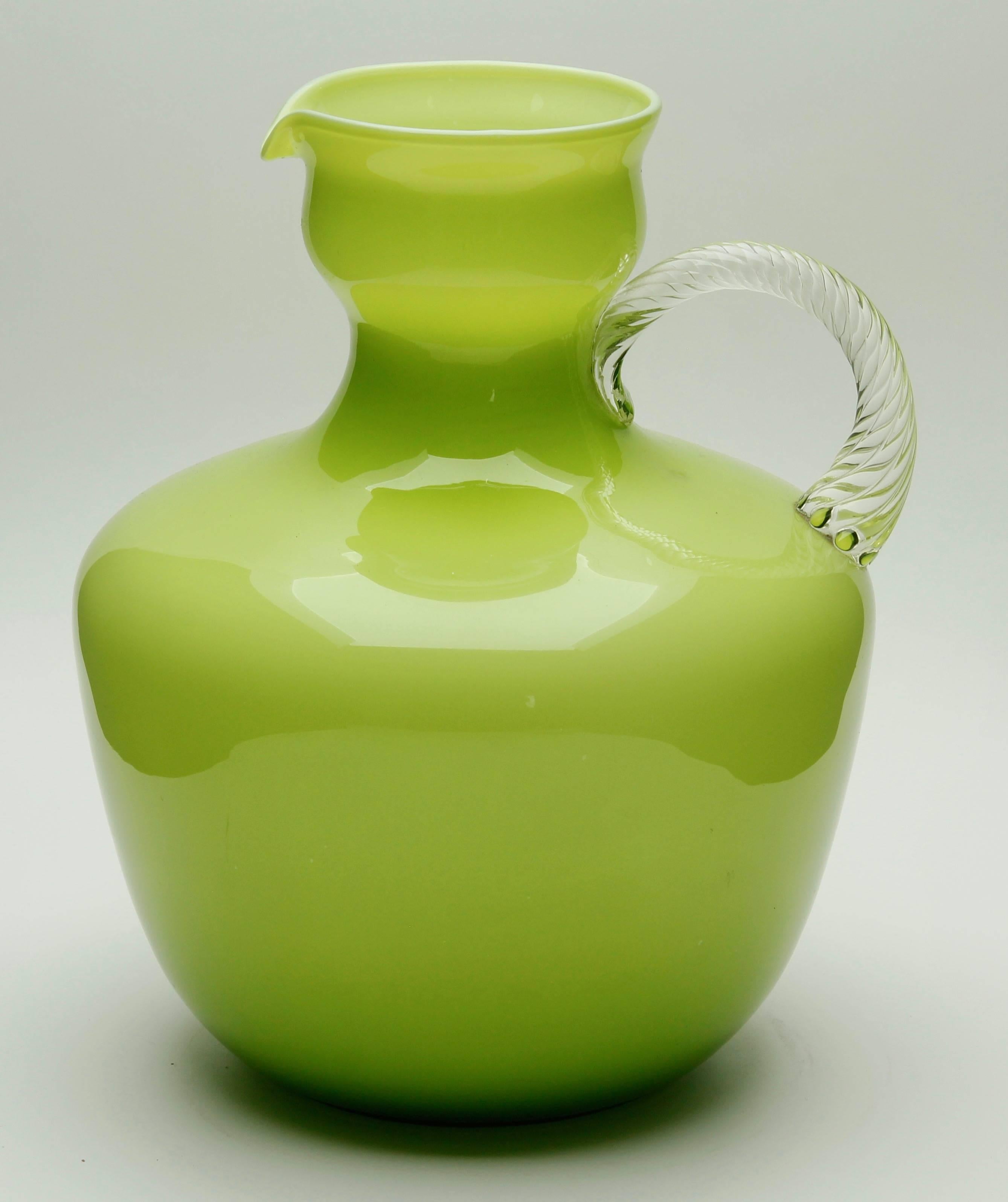 Vintage Italian Empoli olive green Murano cased art glass pitcher

Hand blown cased glass pitcher with twisted handle made in the mid-1955s by the Italian firm Empoli. Irresistibly chic olive green glass encased in clear glass set off by a clear