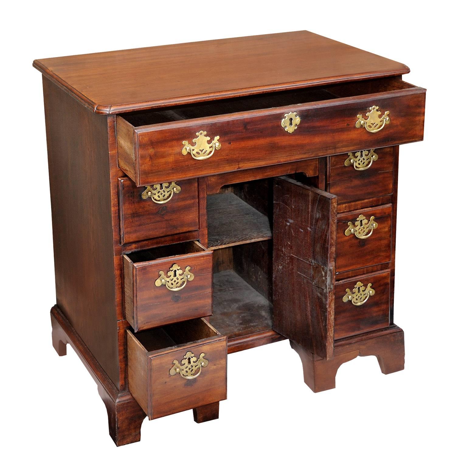 This is a rather charming small 18th century English George III mahogany knee hole desk, standing on bracket feet.

It has seven opening drawers with original brass handles and a central cupboard area with a single shelf and a secret drawer above,