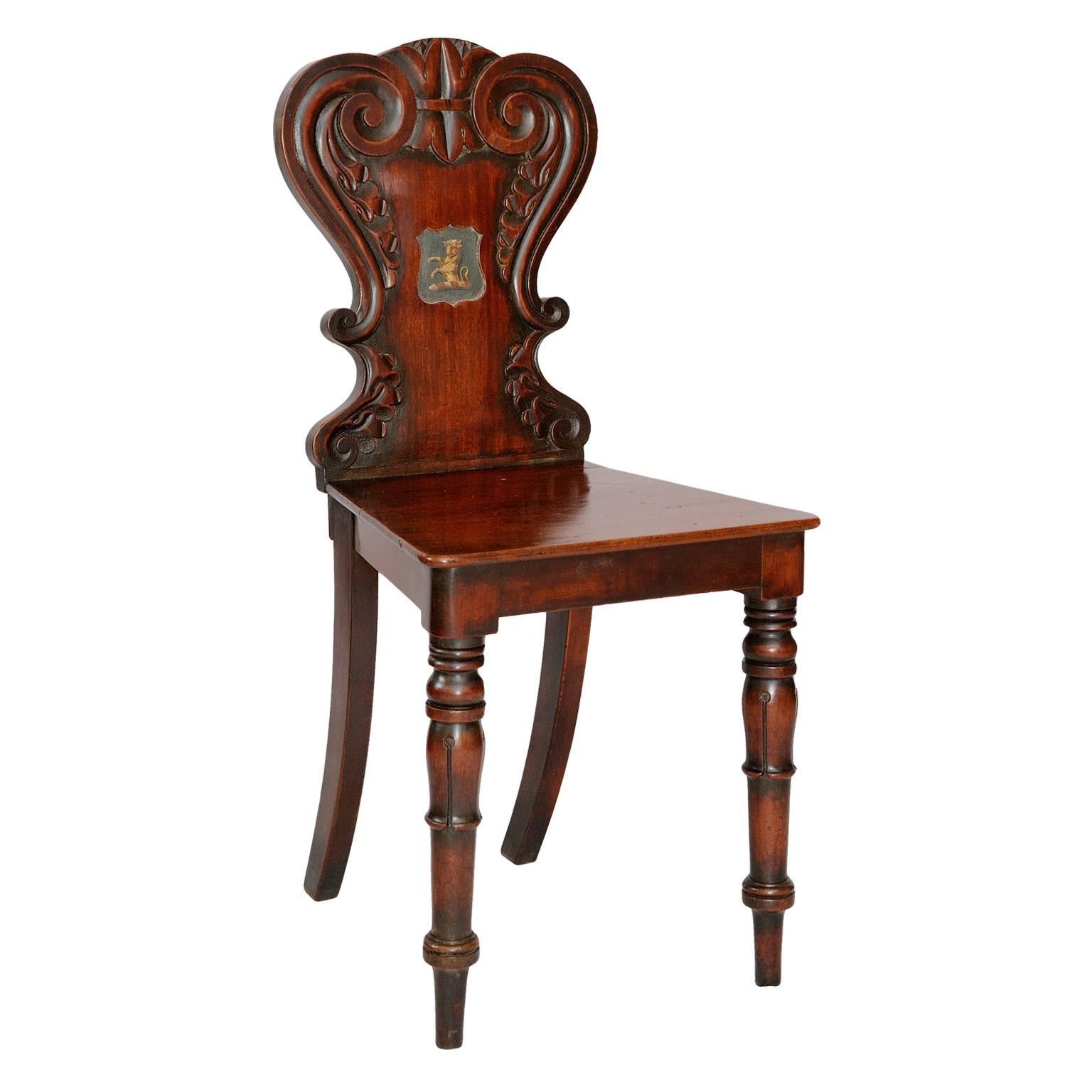 This is a beautiful pair of good quality mahogany late Regency early 19th century English hall chairs, retaining their original painted armorial crest to the back, of a rampant bull (possibly for a family whose name started with Bull ie. Bullman,