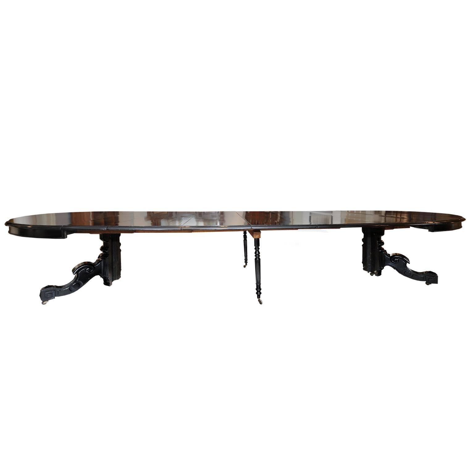 This is an extremely impressive and uniquely versatile large French mid-19th century extending black ebonised Dining Table with six drop-in leaves, extending to over 14' on metamorphic legs and capable of sitting 14+ people. When closed, it forms an