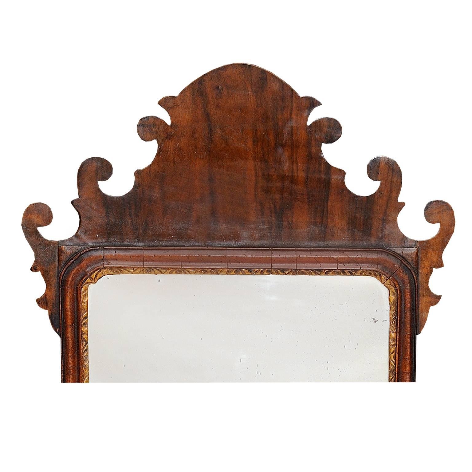 This is a beautiful early 18th century English George II walnut fret mirror with decorative carved giltwood inner border retaining its original mirror plate, circa 1730.