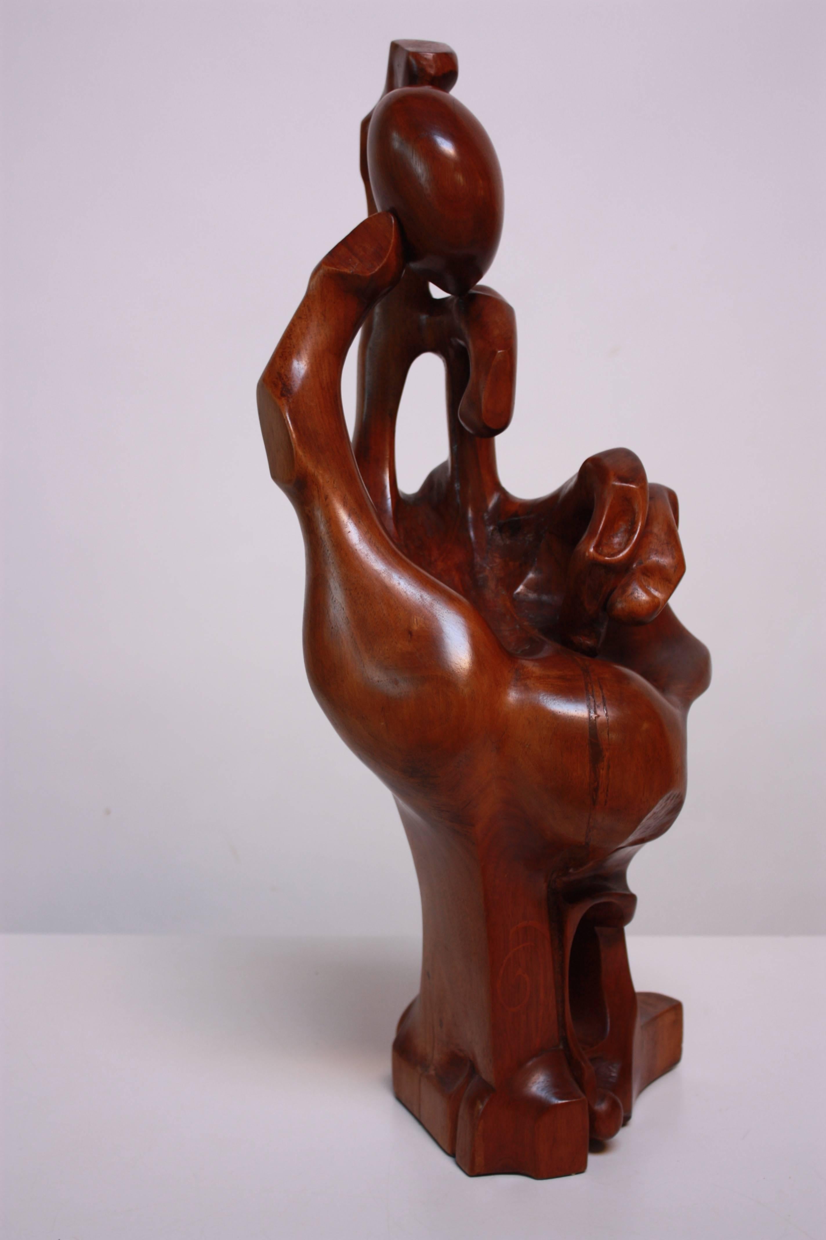 This large, hand-carved wooden sculpture depicts a hand holding a stone and boasts spectacular detail and varying textures and shapes. The work is artist signed by inlay and dated 