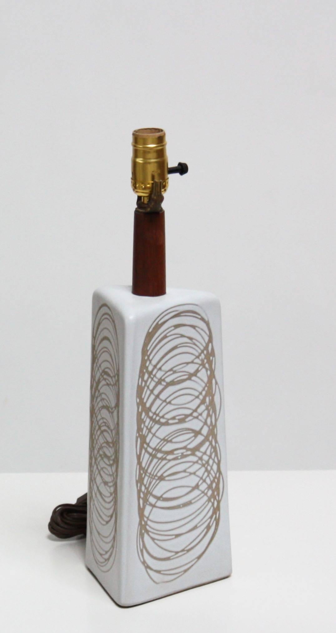 Diese einzigartige Lampe von Jane und Gordon Martz für Marshall Studios hat einen hellgrauen, dreieckigen Sockel mit einem kreisförmigen Sgraffito-Muster in Hellbraun auf allen drei Oberflächen.
 