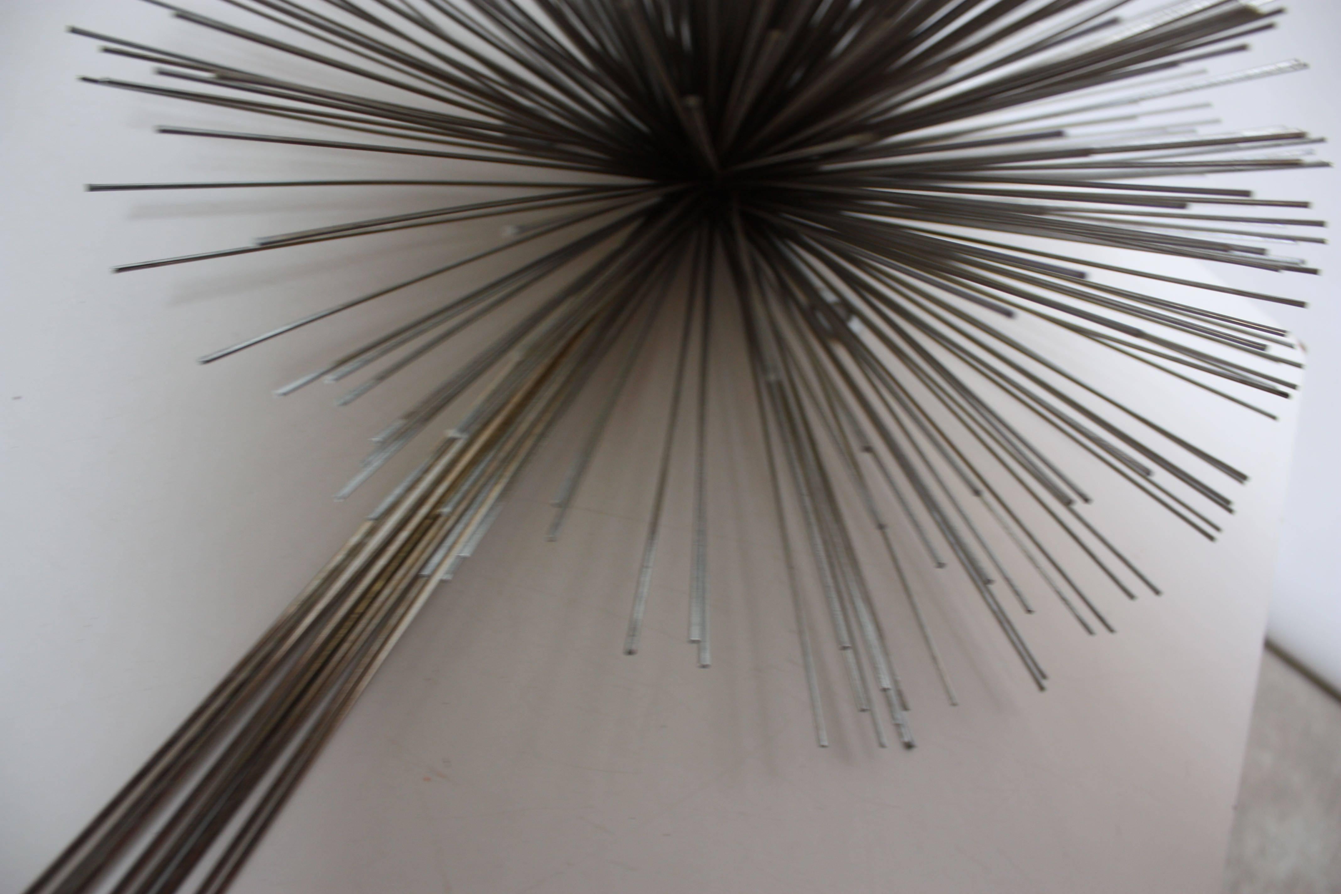 This uncommon Jere sculpture is comprised of chromed steel 'spores' that together form an urchin or pom-pom figure at the top. A combination of brass and chromed steel rods with steel ball tips extend down, and, although the piece does not have the