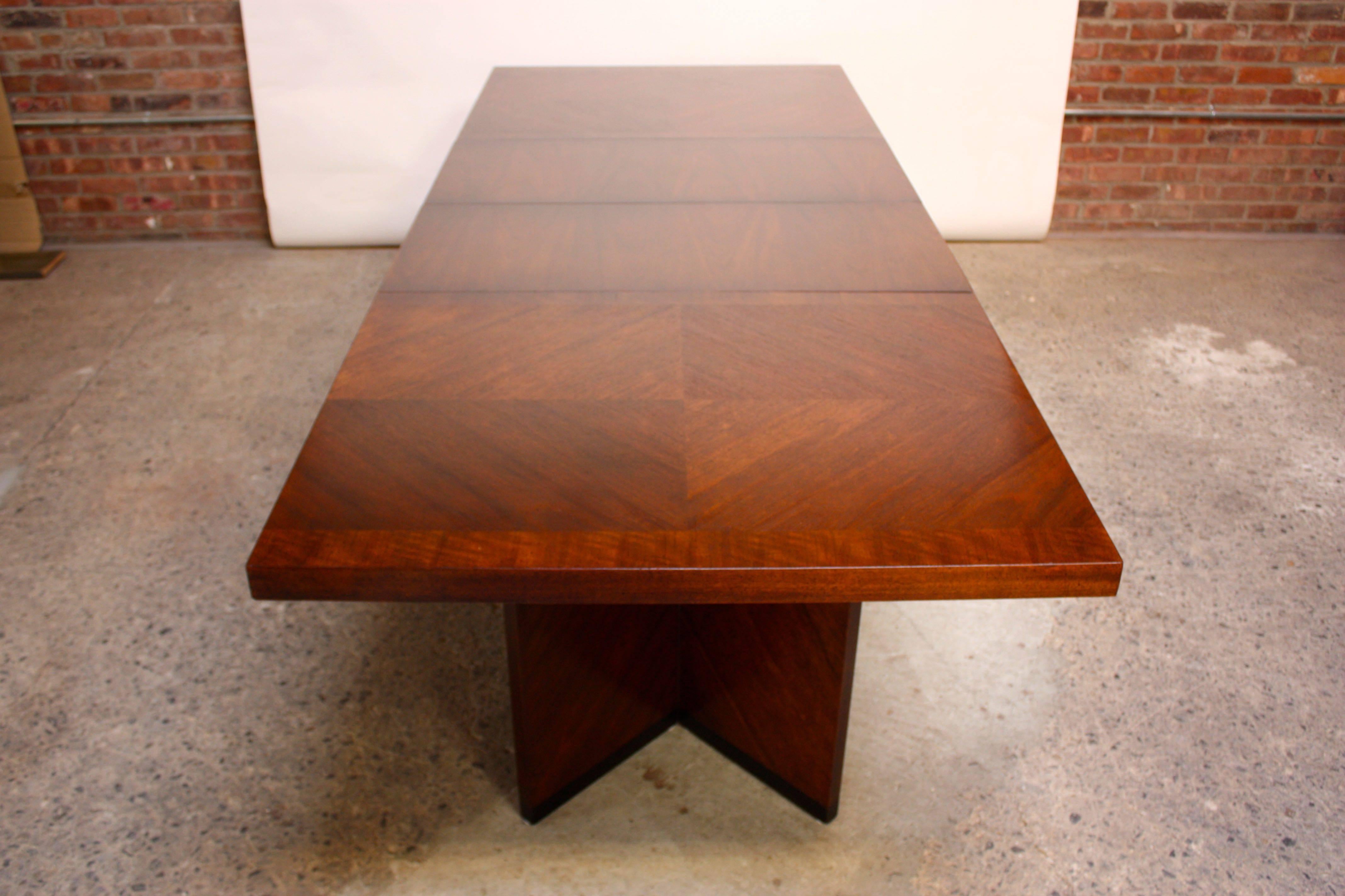 This Brutalist-style walnut table was manufactured by Lane in the 1960s and features two crotch grain walnut veneer extensions which add nice contrast to the parquet checkered pattern on the two stationary ends of the table. The tabletop sits upon