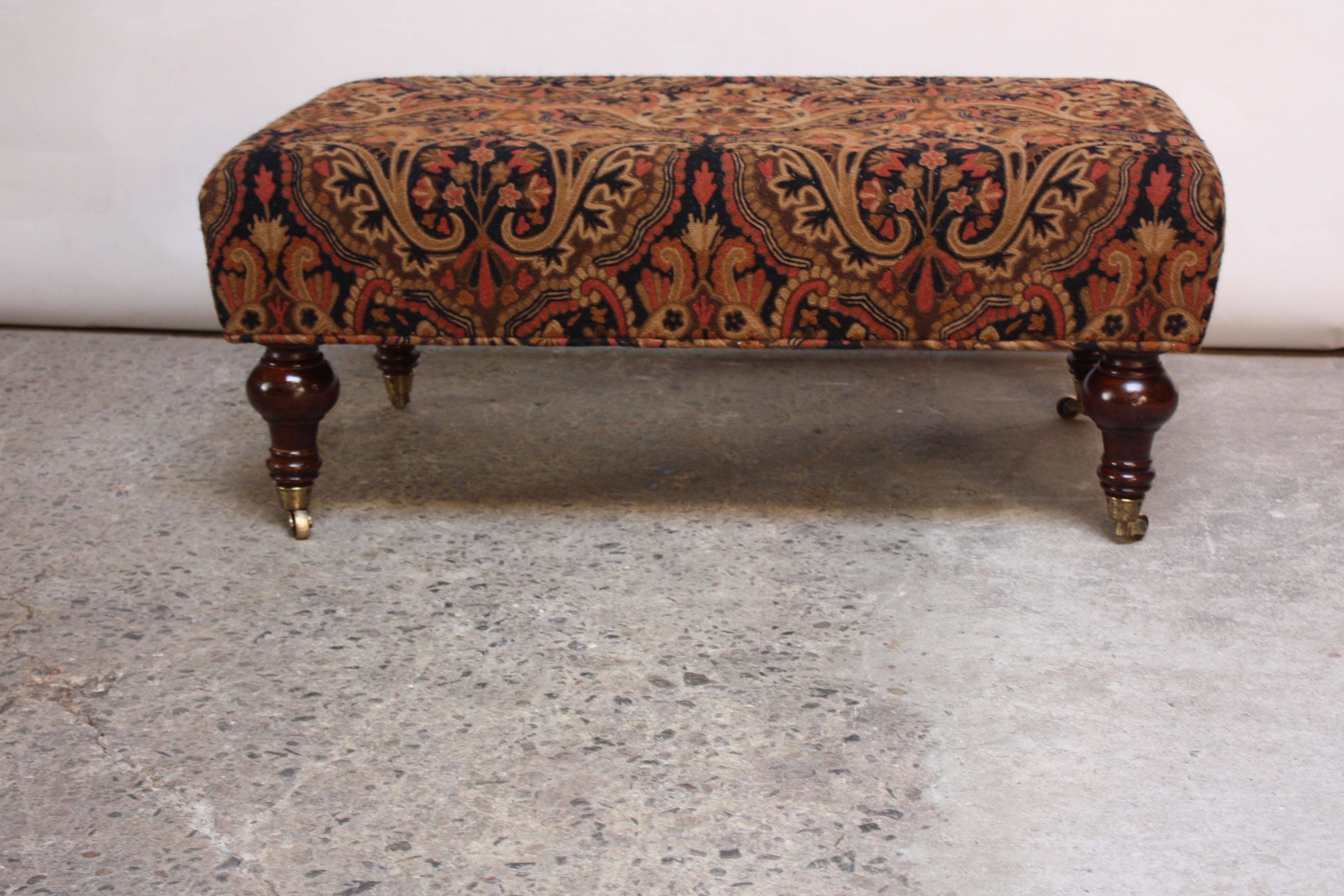 This George Smith ottoman's original upholsetery has been replaced with a vintage crewel fabric. The replacement textile, which bosts bold colors and ornate pattern work, stays true to the original form: George Smith's signature use of heavily