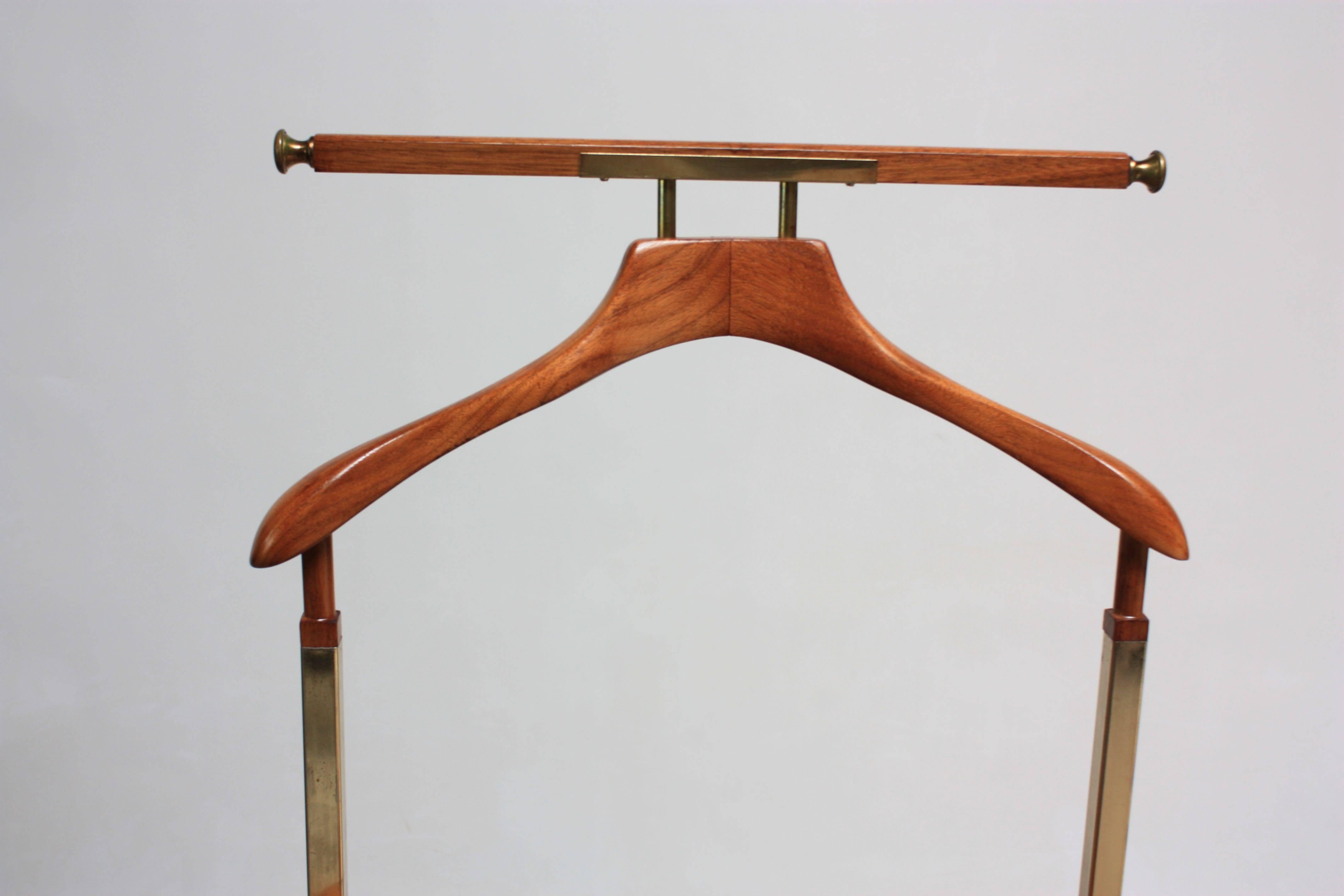 This elegant brass, maple and burl valet stand features an interlinking tubular brass frame, maple hanger and change or cufflink holder, and a cane-topped, burl-veneer drawer. The top bar is intended for hanging scarves, ties, or pants. 
The length