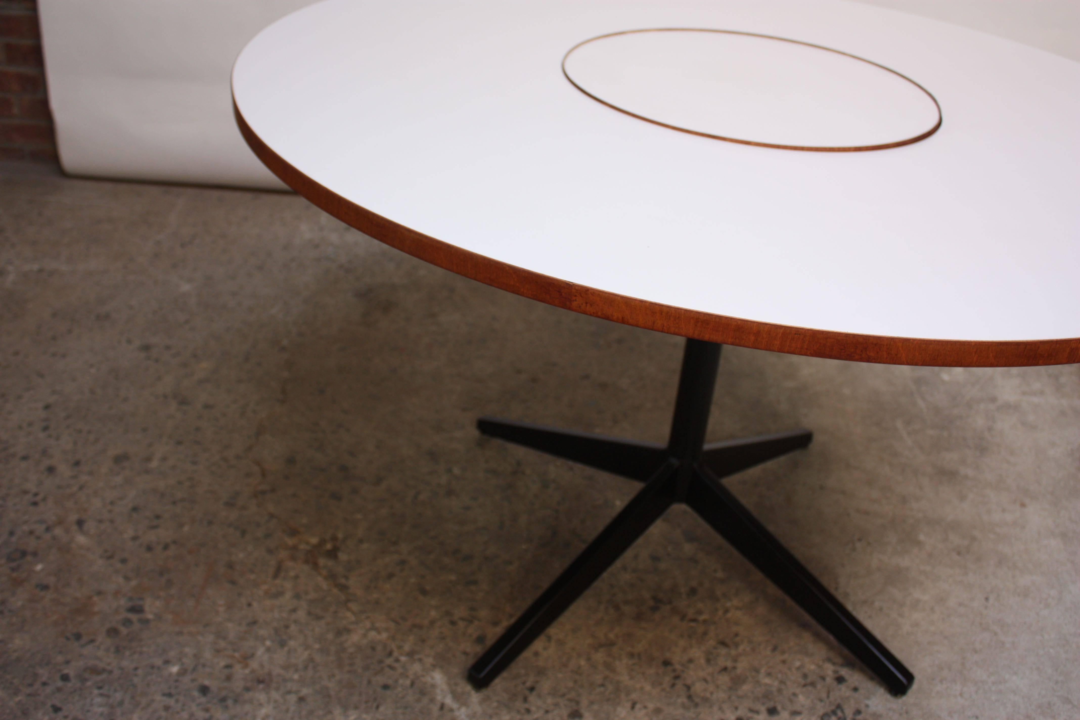 This circular table was designed by George Nelson for Herman Miller in the 1950s and features a white laminate top with rosewood trim. In the center is a functional 'Lazy Susan' which allows for full 360 easy access.