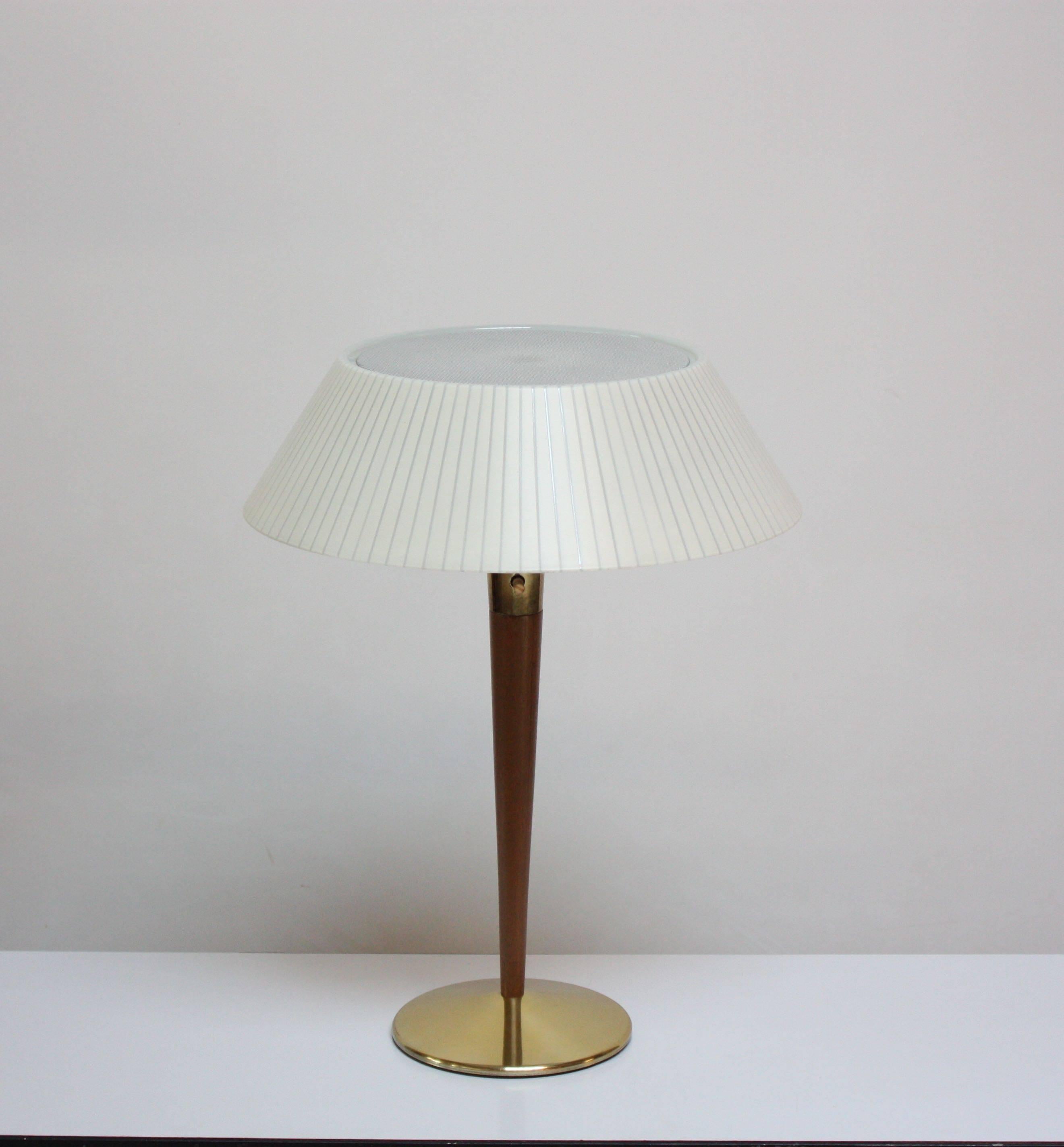 Sculpted walnut and brass table / desk lamp designed by Gerald Thurston for Lightolier. Includes the original plastic shade and perforated, acrylic diffuser. 
Very good, vintage condition with some light scuffing / tarnish to the brass base /