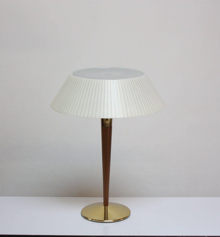 Sculpted walnut and brass table / desk lamp designed by Gerald Thurston for Lightolier. Includes the original plastic shade and perforated, acrylic diffuser. 
Very good, vintage condition with some light scuffing / tarnish to the brass base /