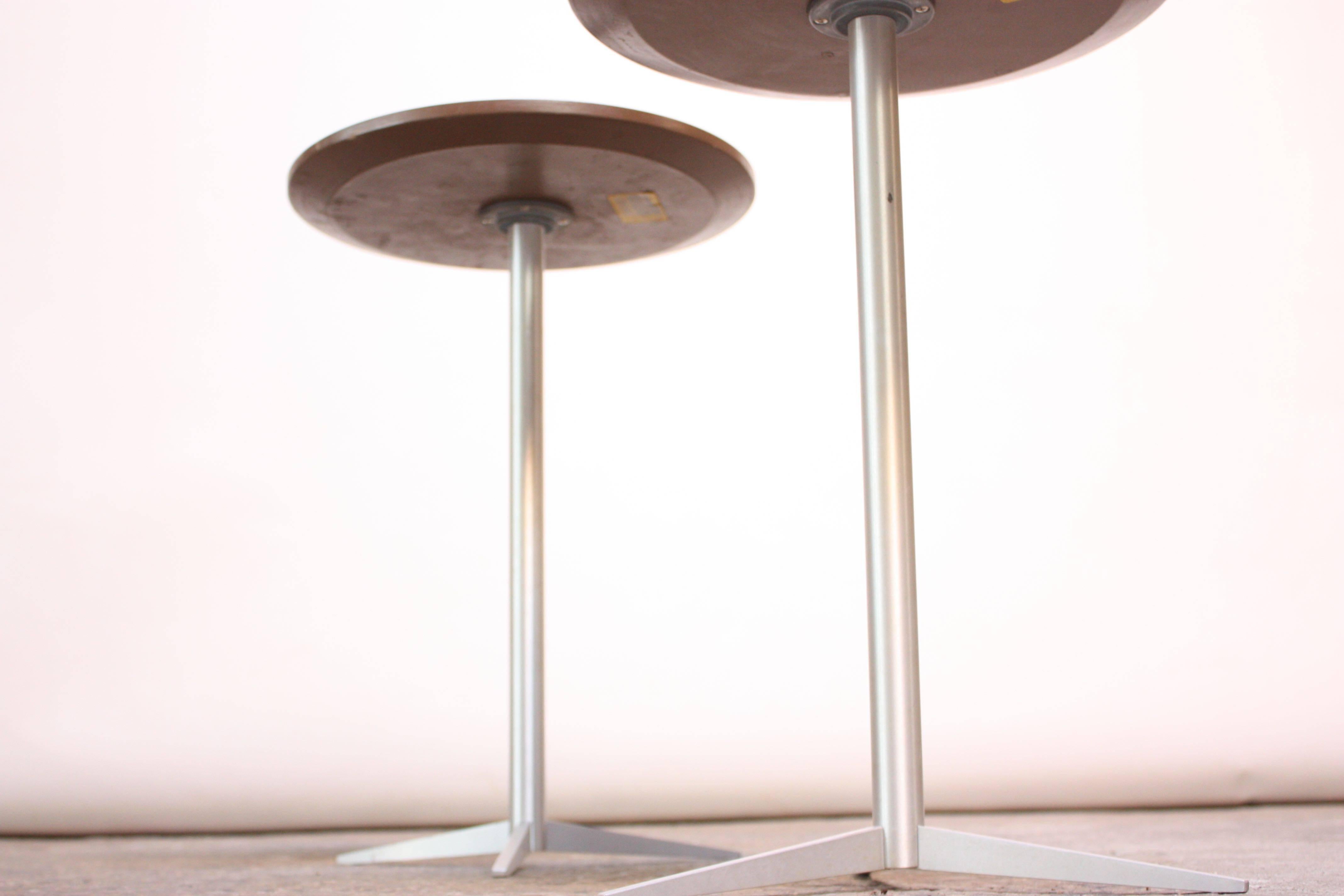 These striking Thonet side or drink tables (often mis-attributed to Paul Mccobb) feature sleek tripod bases in brushed aluminum and laminate round surfaces. The surfaces sit atop a molded plastic base which is screwed onto the aluminum post, so the