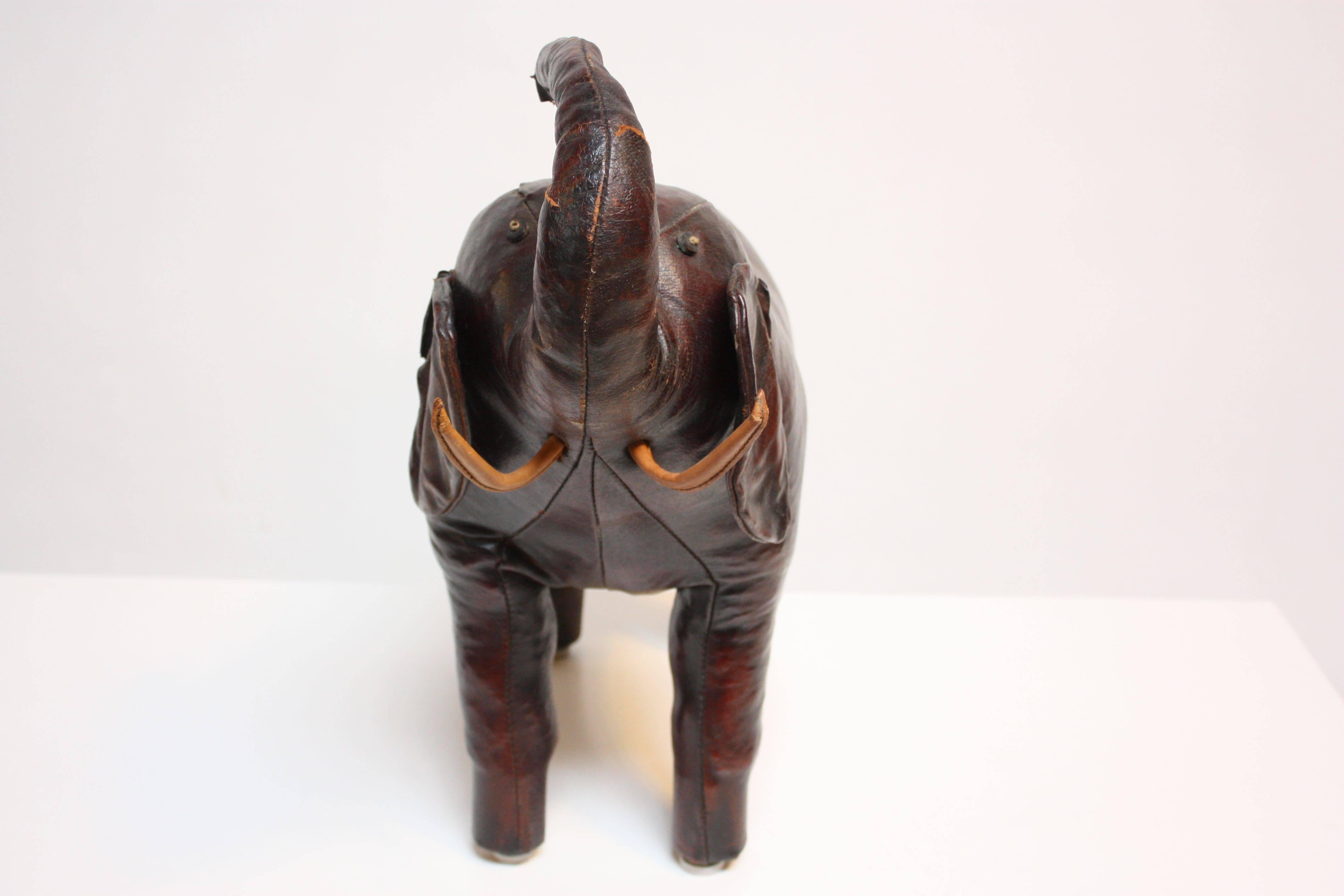 This whimsical elephant ottoman/doorstop was designed by Dimitri Omersa for Abercrombie and Fitch in the 1970s. This is a wonderful example that boasts rich color and detailed construction. There is wear, namely a tear through the trunk which