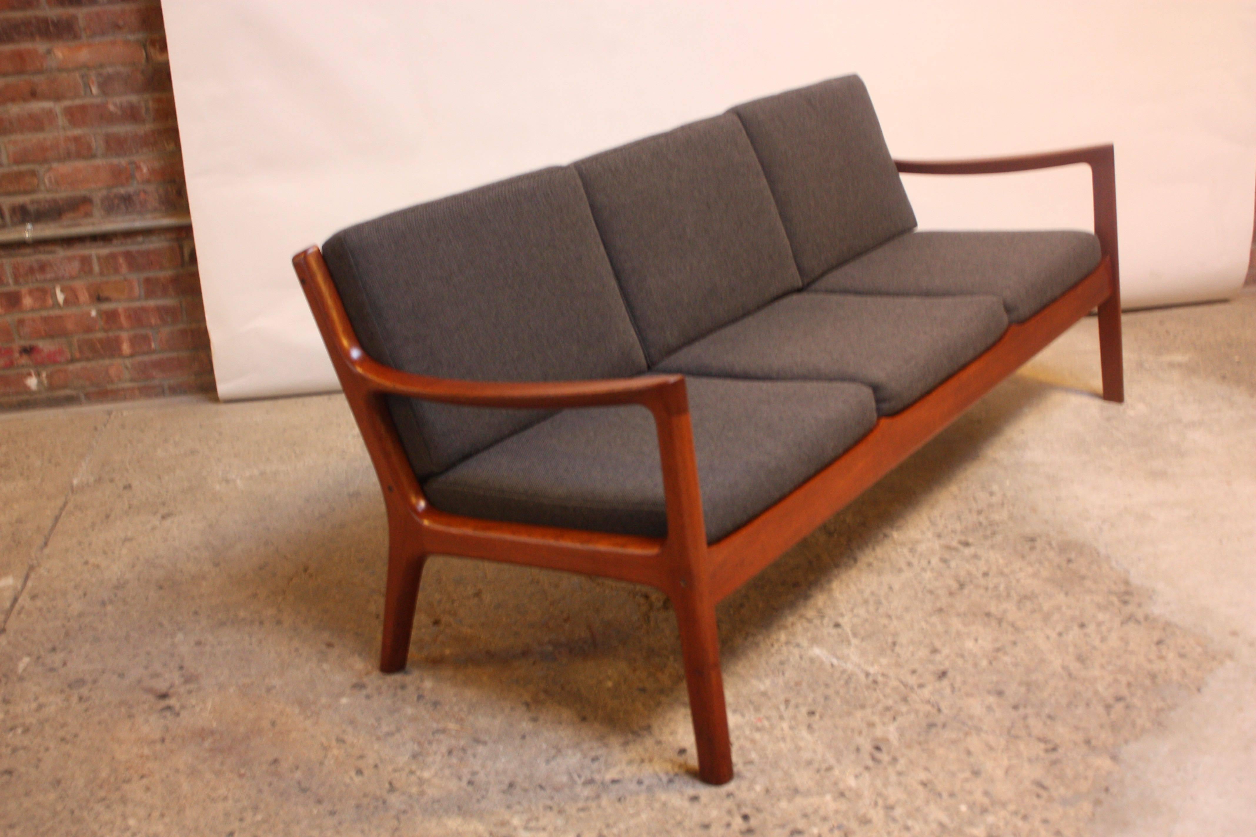 This teak three-seat sofa was designed by Ole Wanscher for France & Son as part of his 'Senator' line. This example is an early France & Son production (1965, as indicated by the stamp) and retains two manufacturer medallions to the frame. This