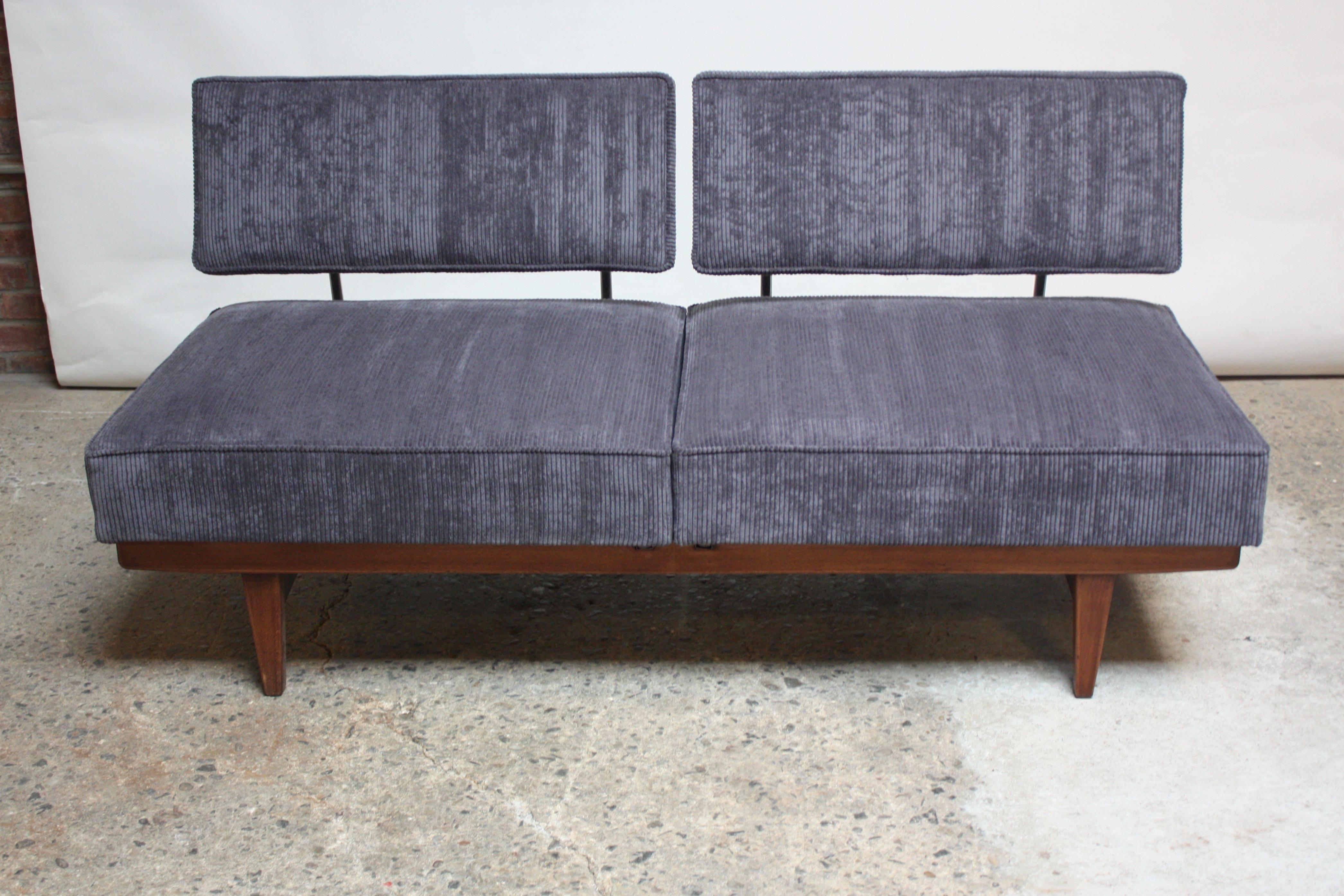 This Danish walnut convertible sofa is comprised of two seats (joined to their respective headrests by tubular chromed steel supports) which can be turned inward to convert from sofa into daybed. When the seats are turned on the frame's track, the