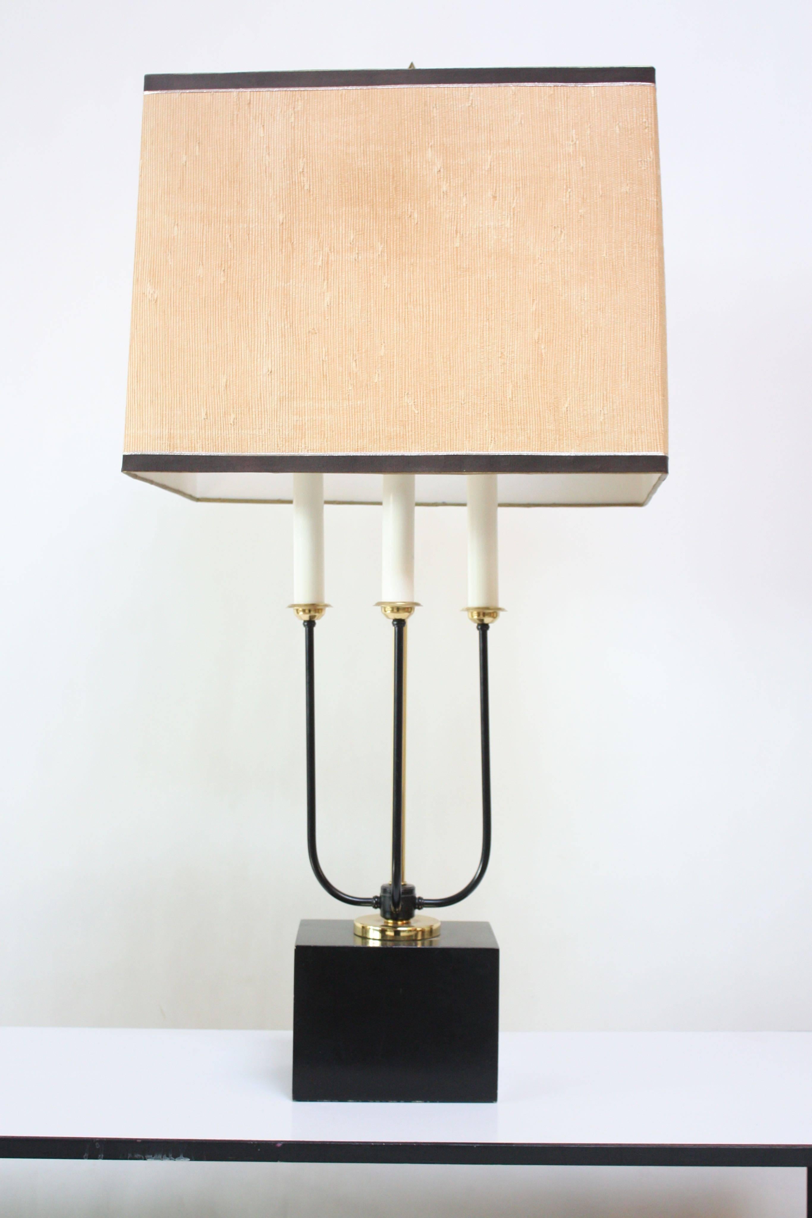 This bouillotte style table lamp is comprised of three metal 'candle' tapers supported by brass and metal stems on a molded aluminium base. There is only one illumination setting by way of a rotary switch with three tapers for bulbs. The shade can