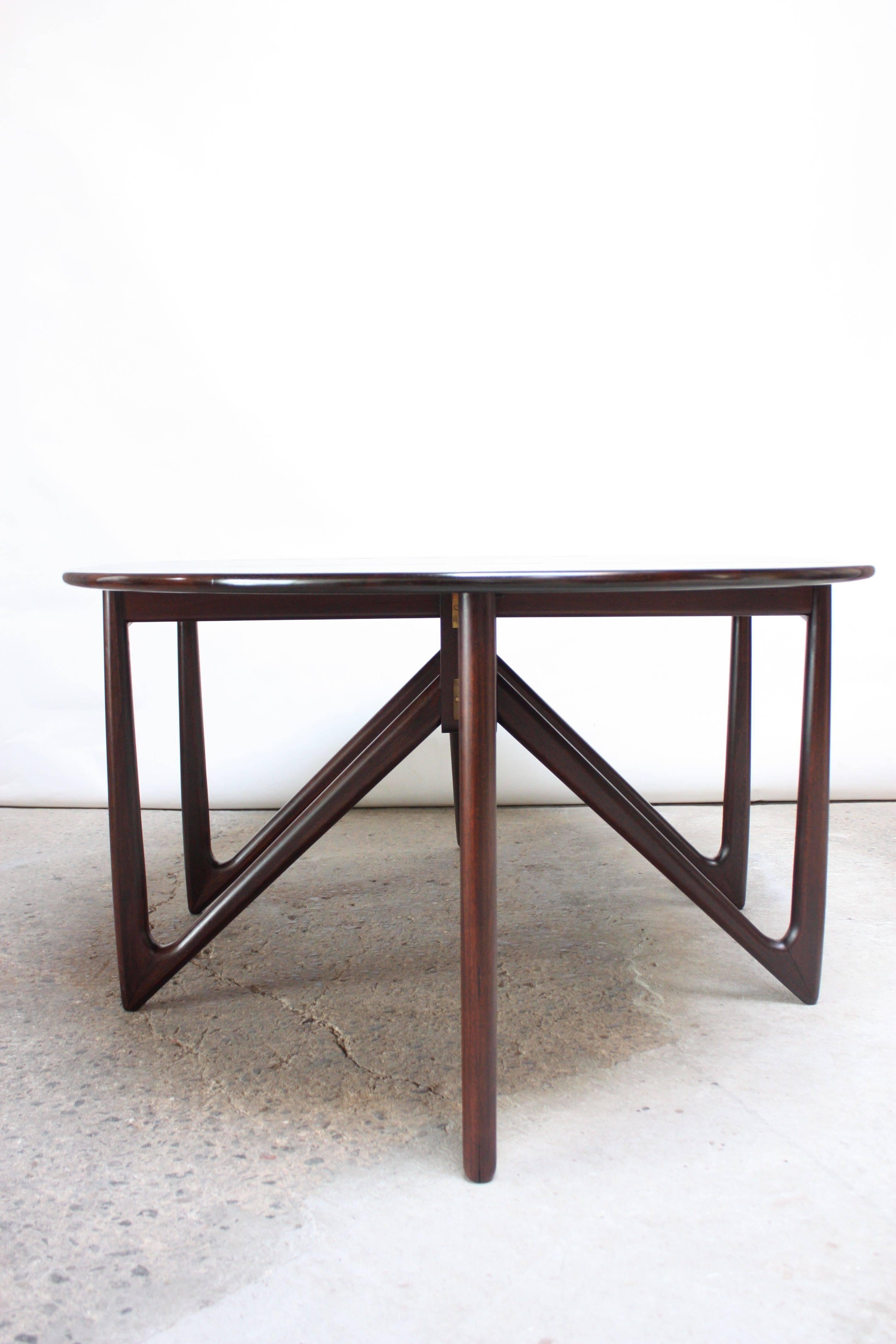This spectacular rosewood dining table was designed by Niels Koefoed for Koefoeds Hornslet in 1964 (frequently mis-attributed as Kurt Østervig for Jason Møbler) and features an elliptical top over folding V-legs. The drop leaves move up and down on