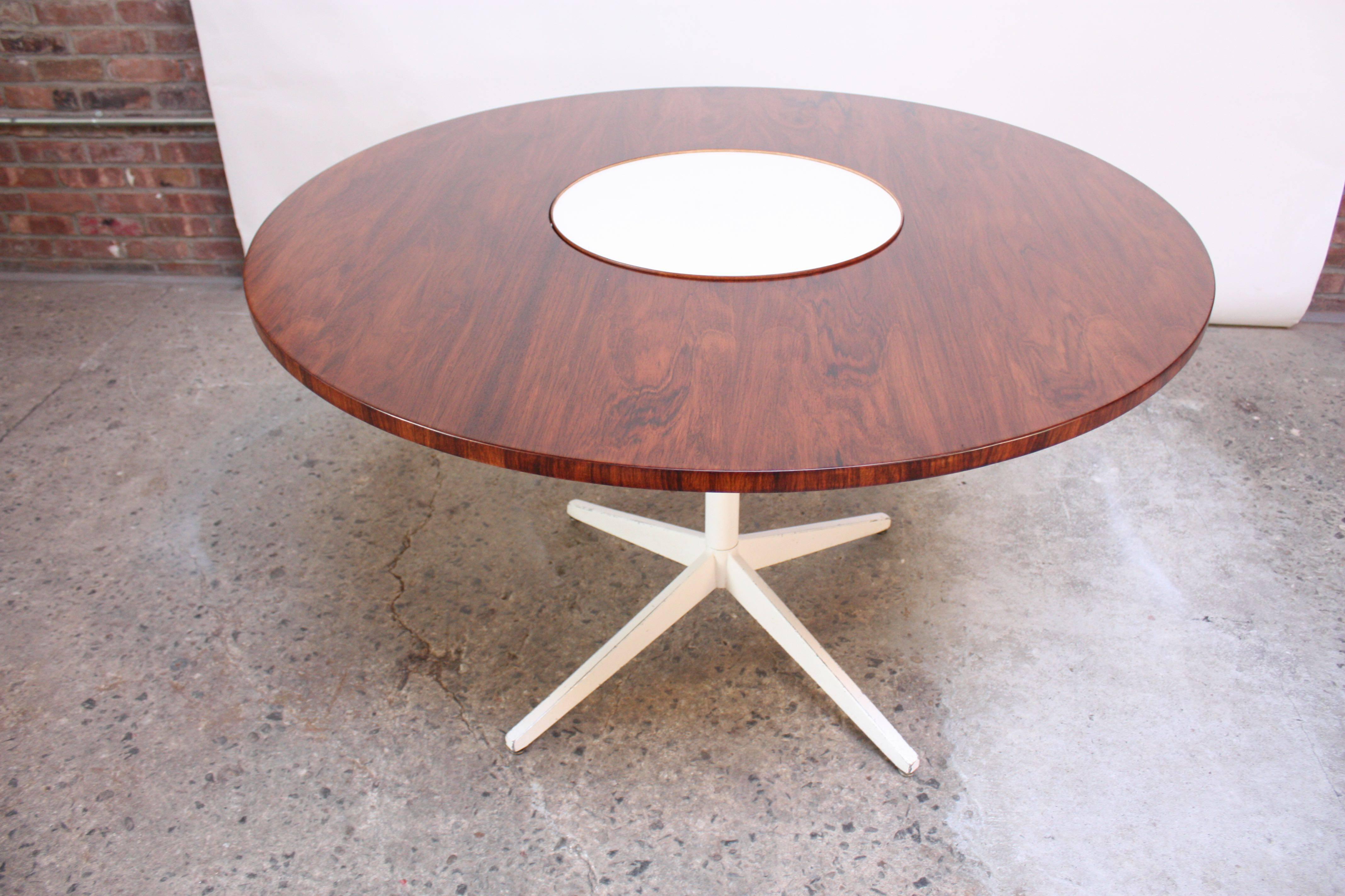 This circular table was designed by George Nelson for Herman Miller in the 1950s and features a rosewood top and trim. In the center is a functional 'Lazy Susan' in white laminate, insulated in rosewood, allowing for full 360 easy access. This
