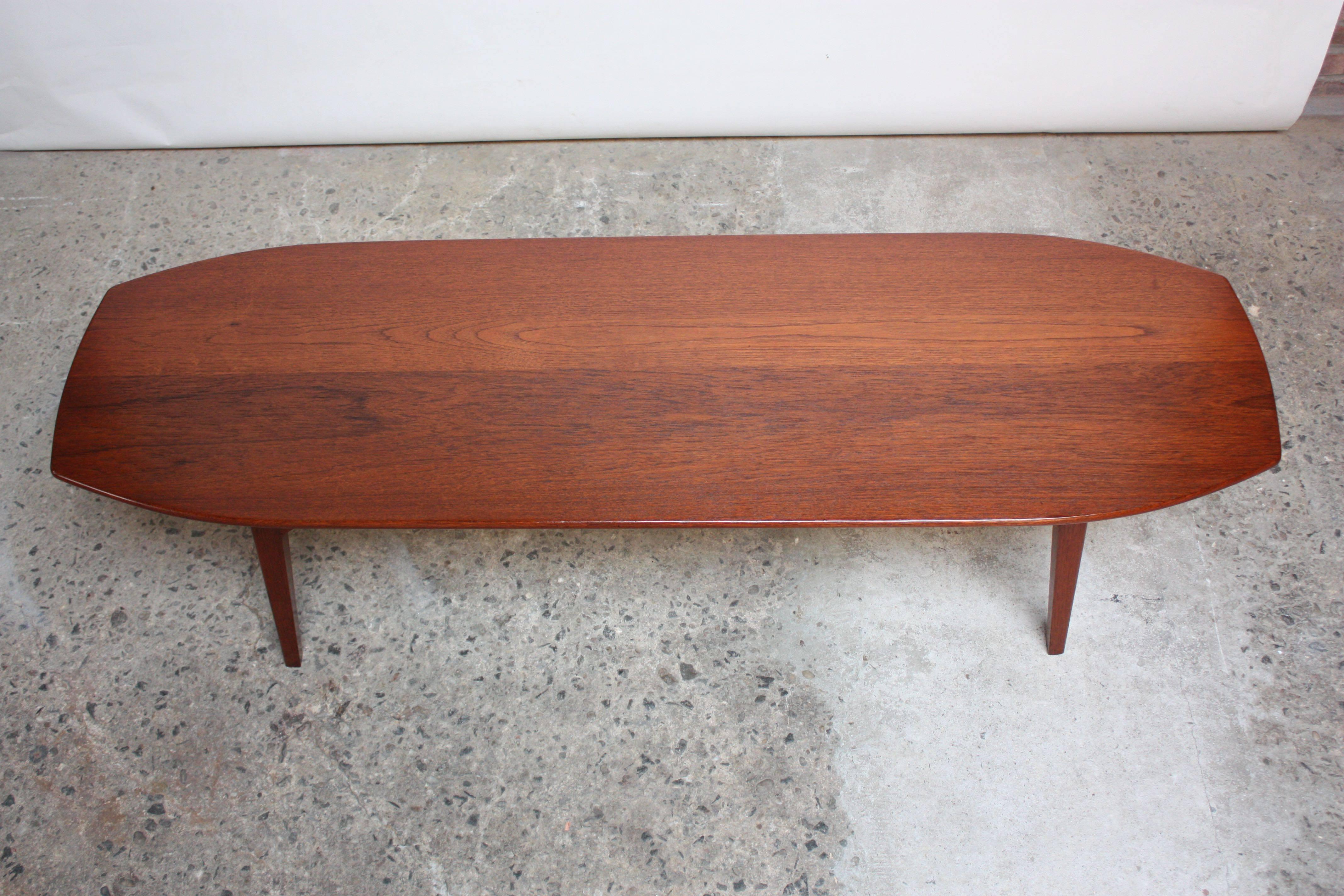 This teak coffee table, characterized by an irregular octagonal surfboard surface, is elegant in its simplicity. There is no veneer work to this piece; it is solid teak from the surface to the base. Beautiful, restored condition.