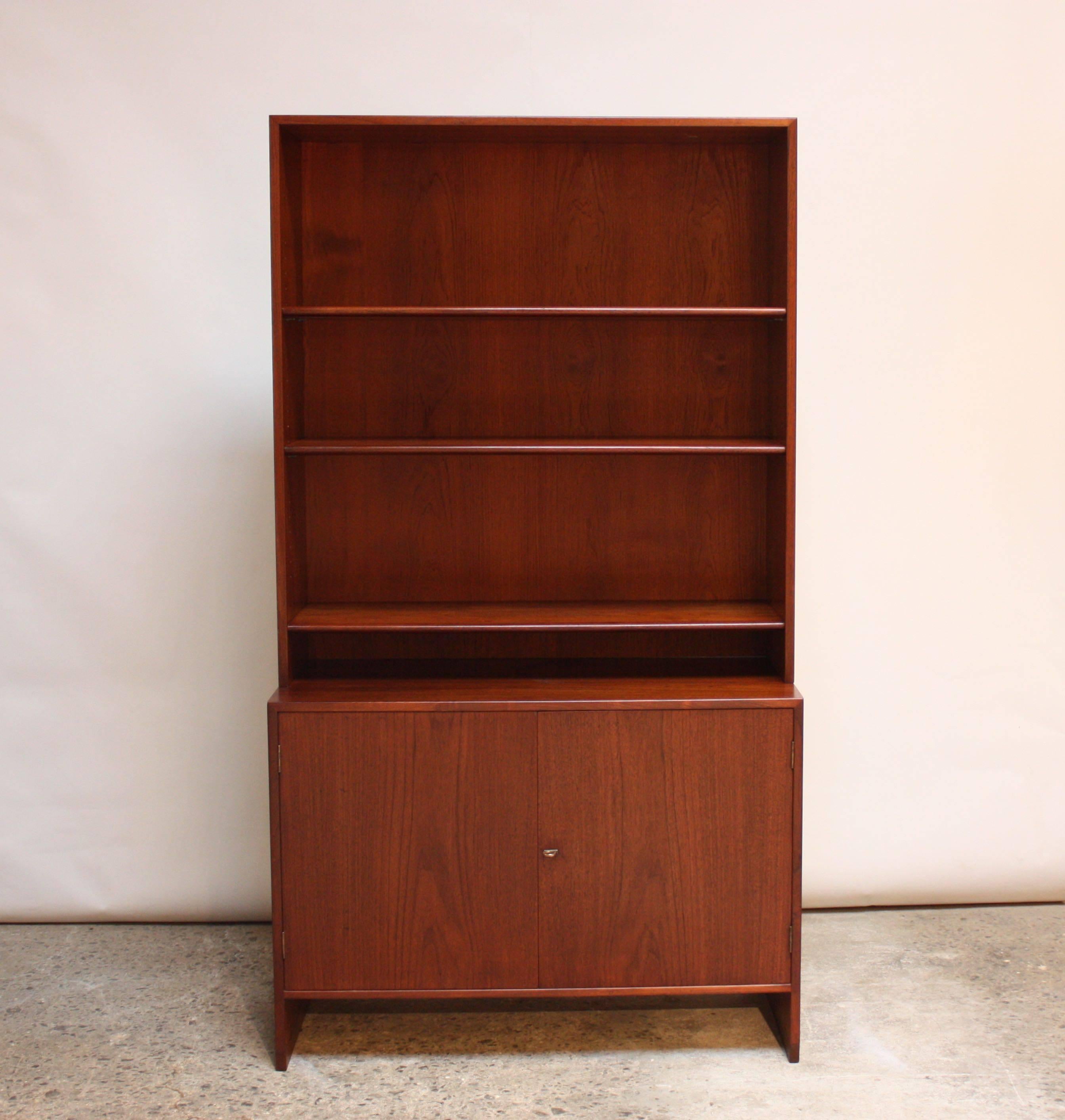 This two-piece bookcase unit (model RY 100) was designed by Hans Wegner for Ry Mobler. These pieces can be used separately as a free-standing bookshelf and cabinet, respectively, or stacked to create this compact unit.
Both shelves to the top