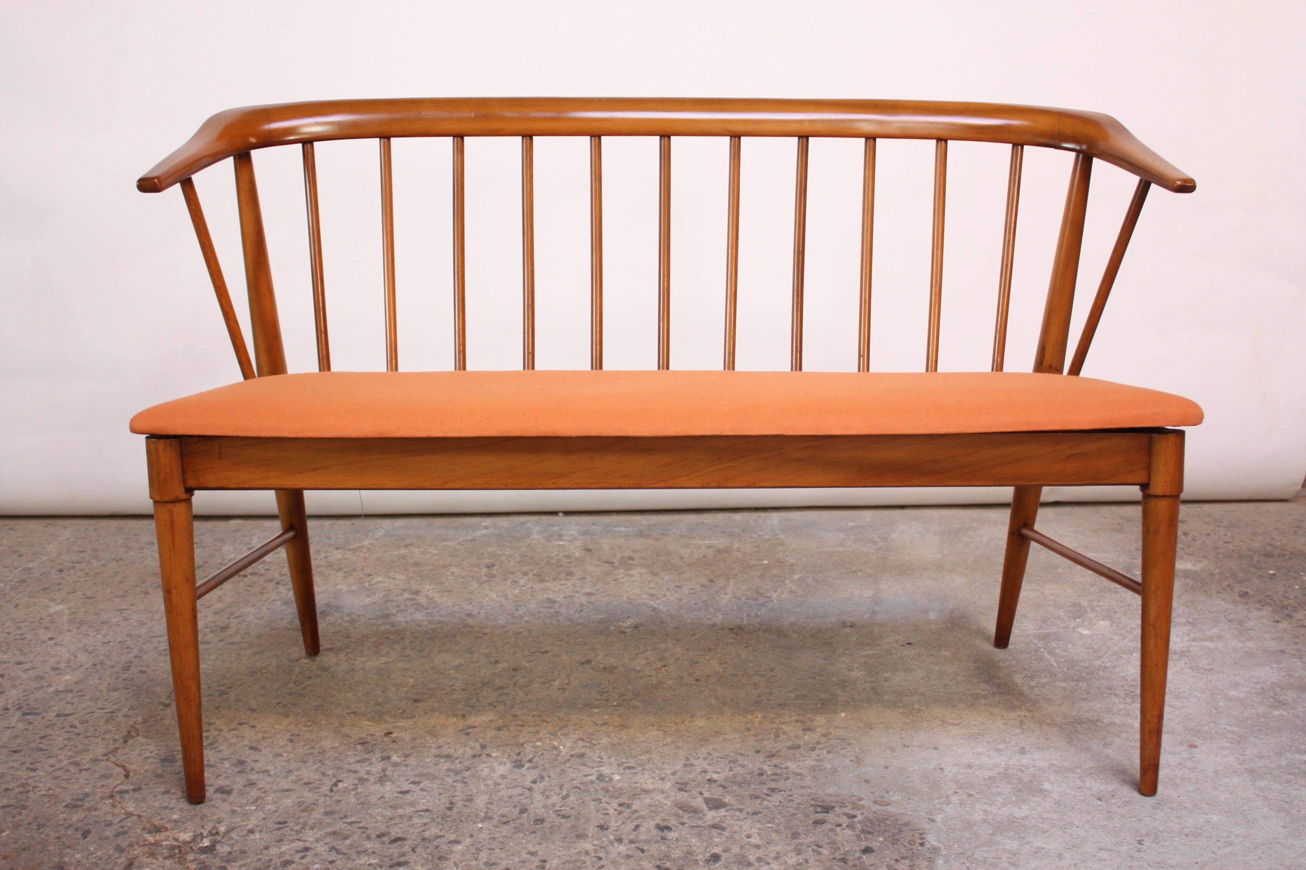 This Shaker-style American walnut bench features a spindle-back construction with a curved back arm or backrest.
The vintage linen upholstery was salvaged, as the previous owner covered over this original fabric. The fabric is in excellent, vintage