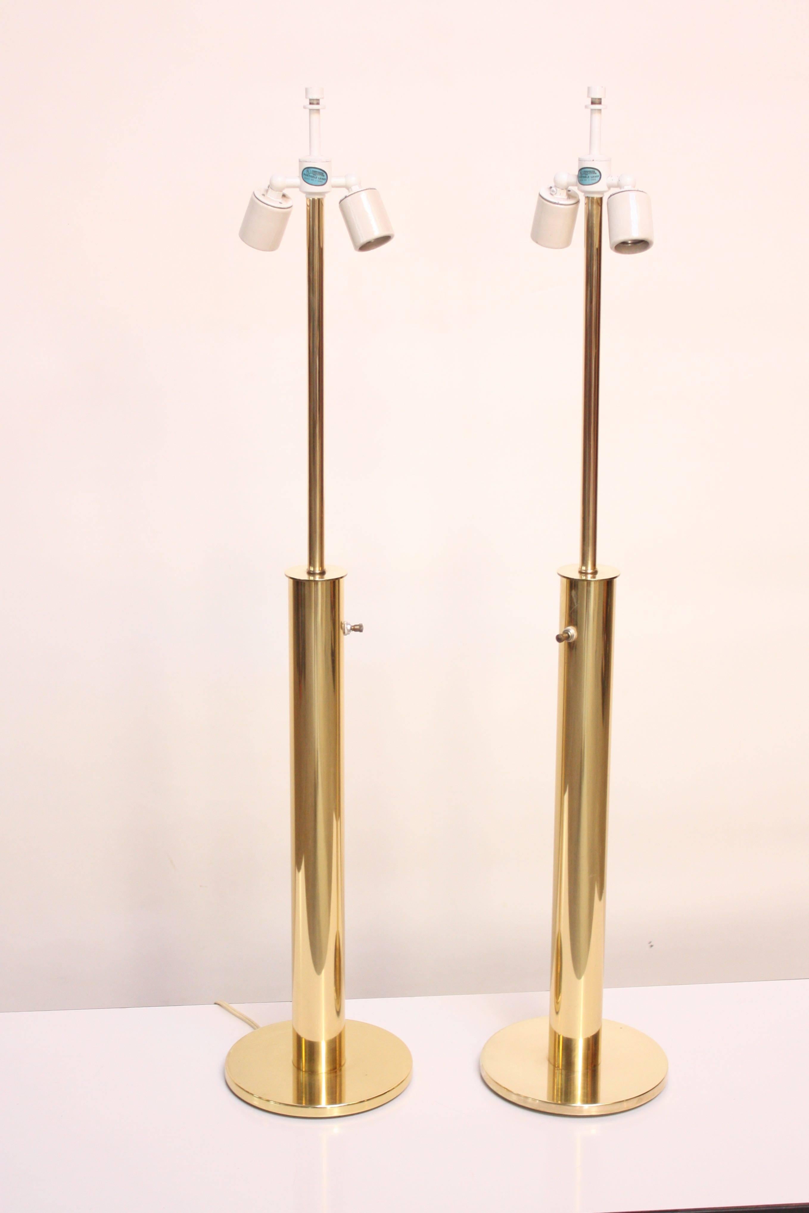 This pair of simple, yet glamorous table lamps are composed of elongated cylindrical stems connected to circular bases. Double porcelain sockets and original switch are intact, but the wiring is new. Brass has been perfectly polished and shows no