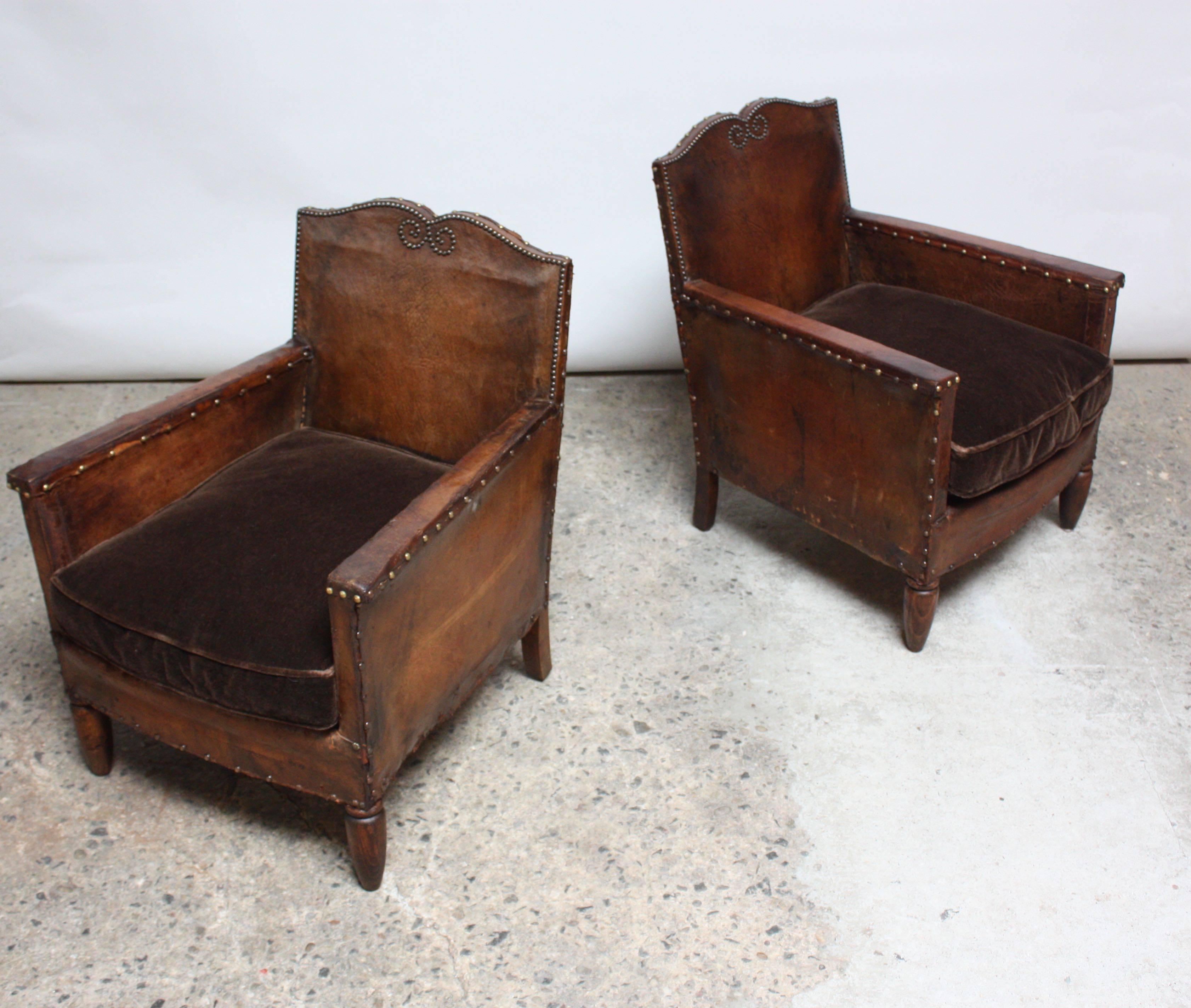 These small club chairs were designed in France between the mid-1920s through the early 1930s and are composed of leather frames and velvet cushions (an upholstery contrast that was typical for the period). However, the cushions were likely updated