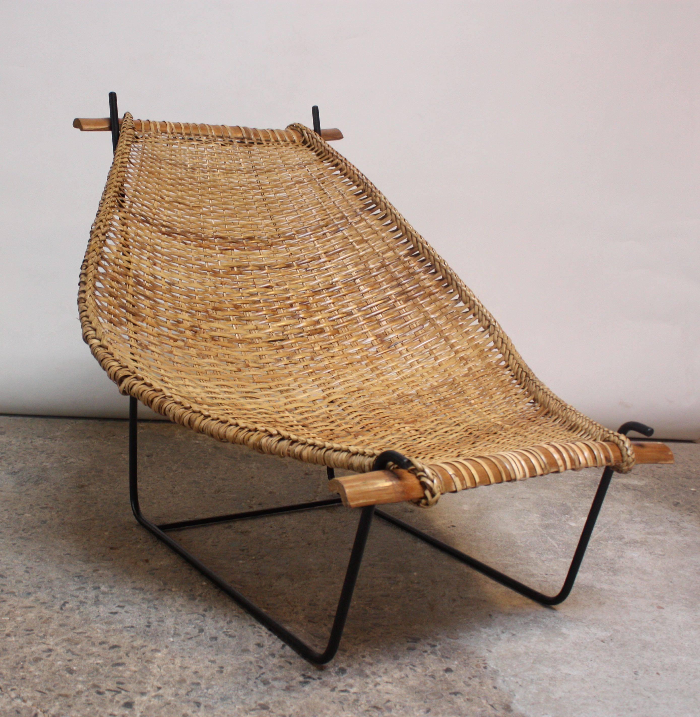 This unique lounge chair was designed in 1953 by John Risley for Ficks Reed. A combination of braiding and weaving techniques were used to create the rattan 'basket,' which is anchored at both top and bottom by carved bamboo rails. This basket seat