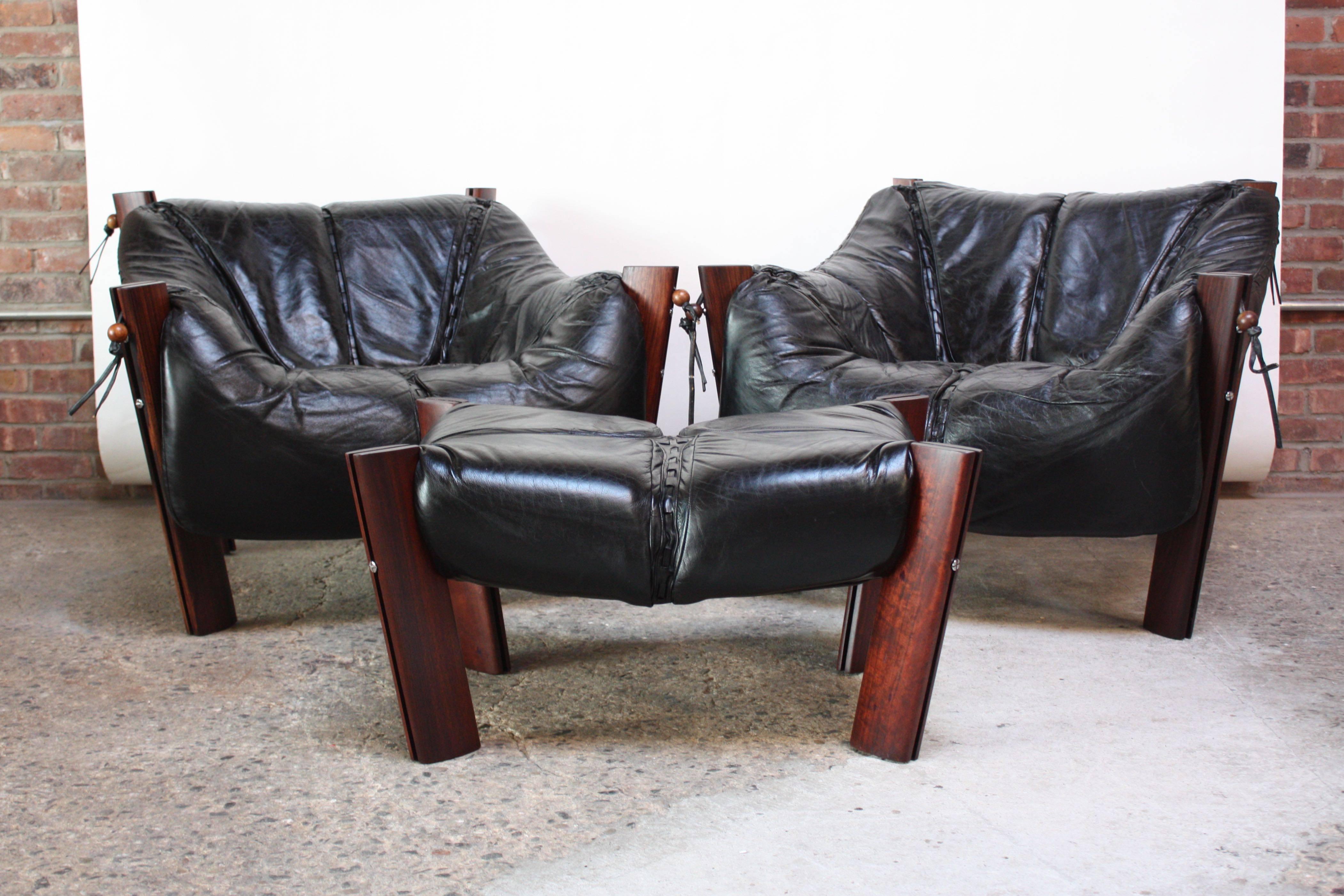 Set of two lounge chairs and one ottoman designed by Percival Lafer in Sao Paolo, Brazil in 1975. Leather 'sling' seats are supported by steel enforced jacaranda posts. Round rosewood beads and leather ties re-enforce the seats to the posts and add