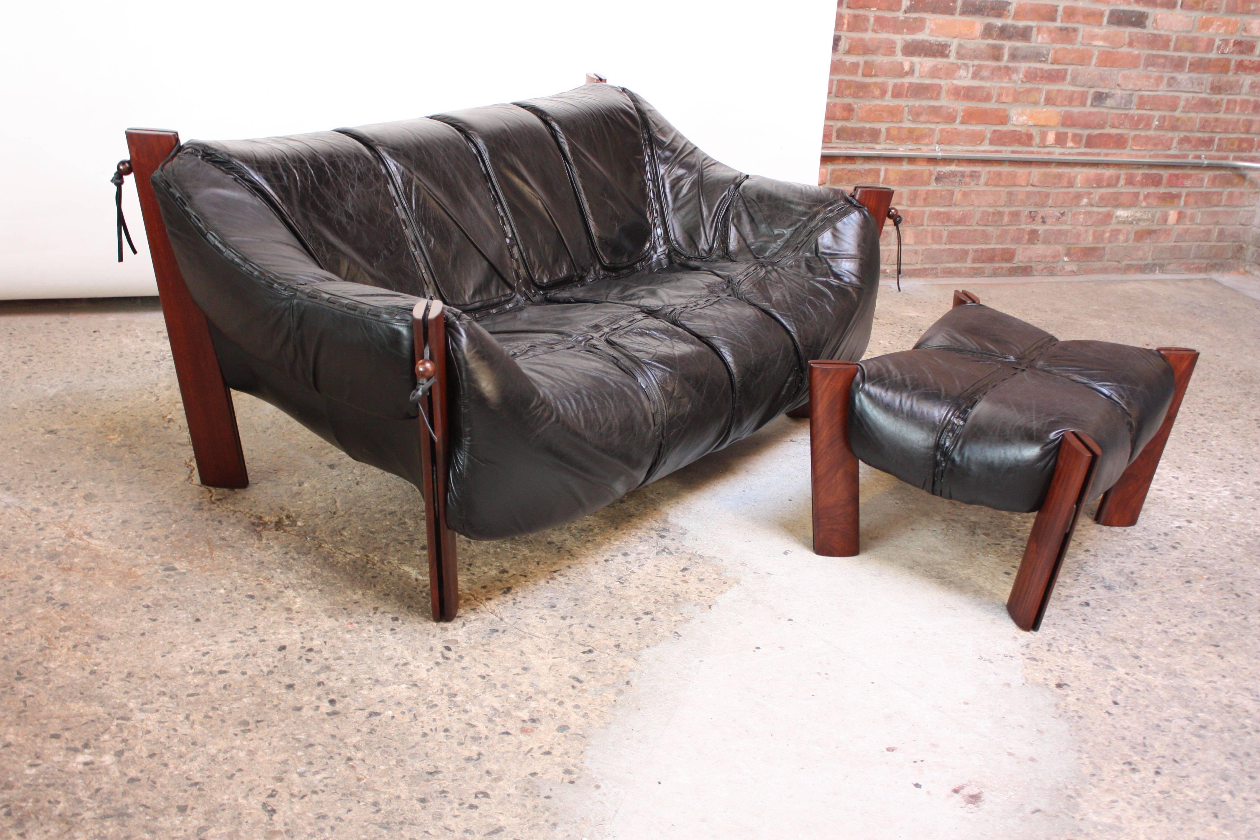 Sleek two-seat leather sofa designed by Percival Lafer in Sao Paolo, Brazil in 1975. Single leather 'sling' seat fits into the molded resin frame and is supported by steel enforced jacaranda posts. Round rosewood beads and leather ties re-enforce