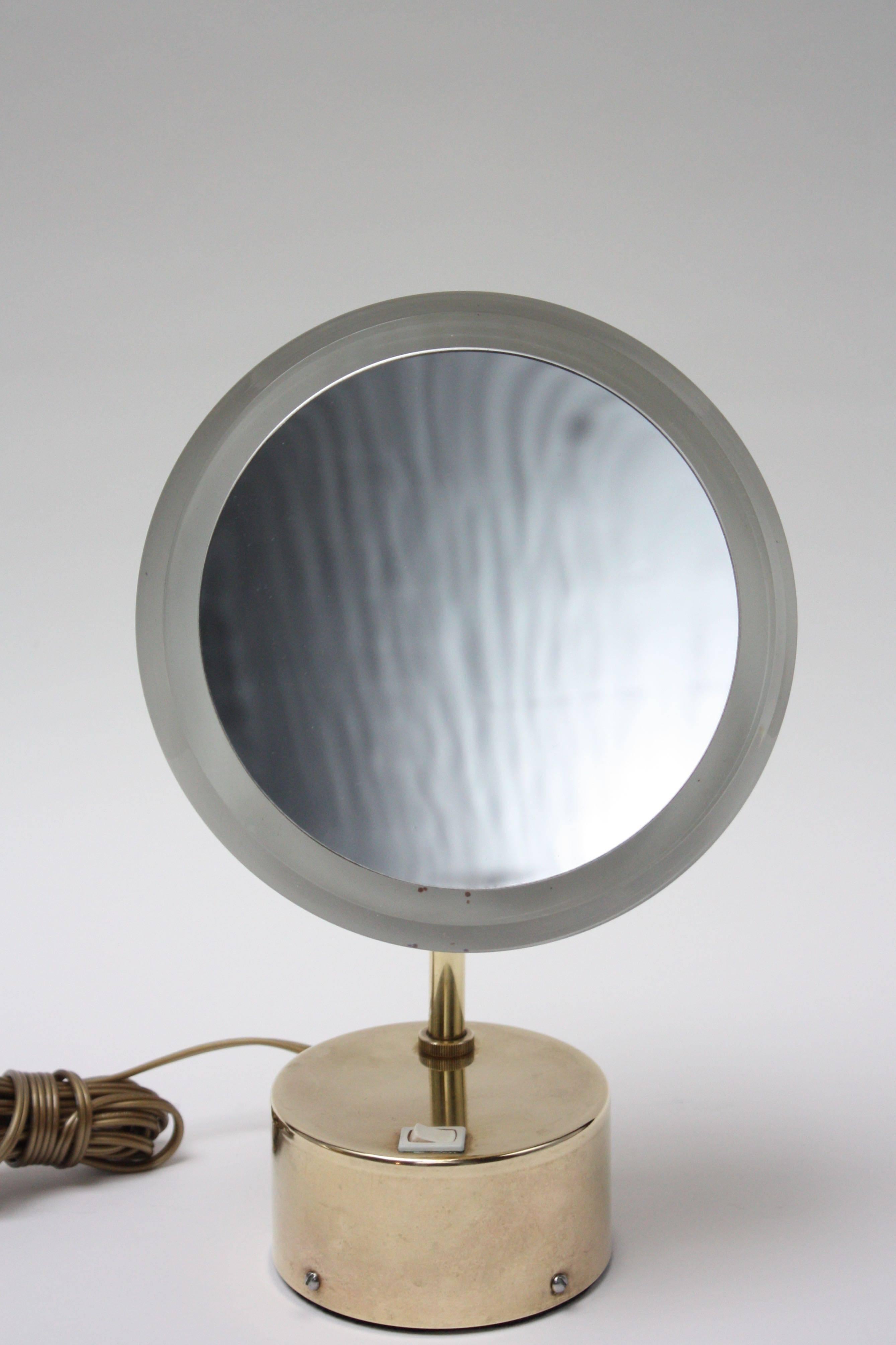1960s solid brass vanity mirror in excellent, polished condition. The mirror is framed with a band of Lucite; the rest of the lamp is solid brass. The mirror itself can be removed by unscrewing the back mounts to change the lightbulb.