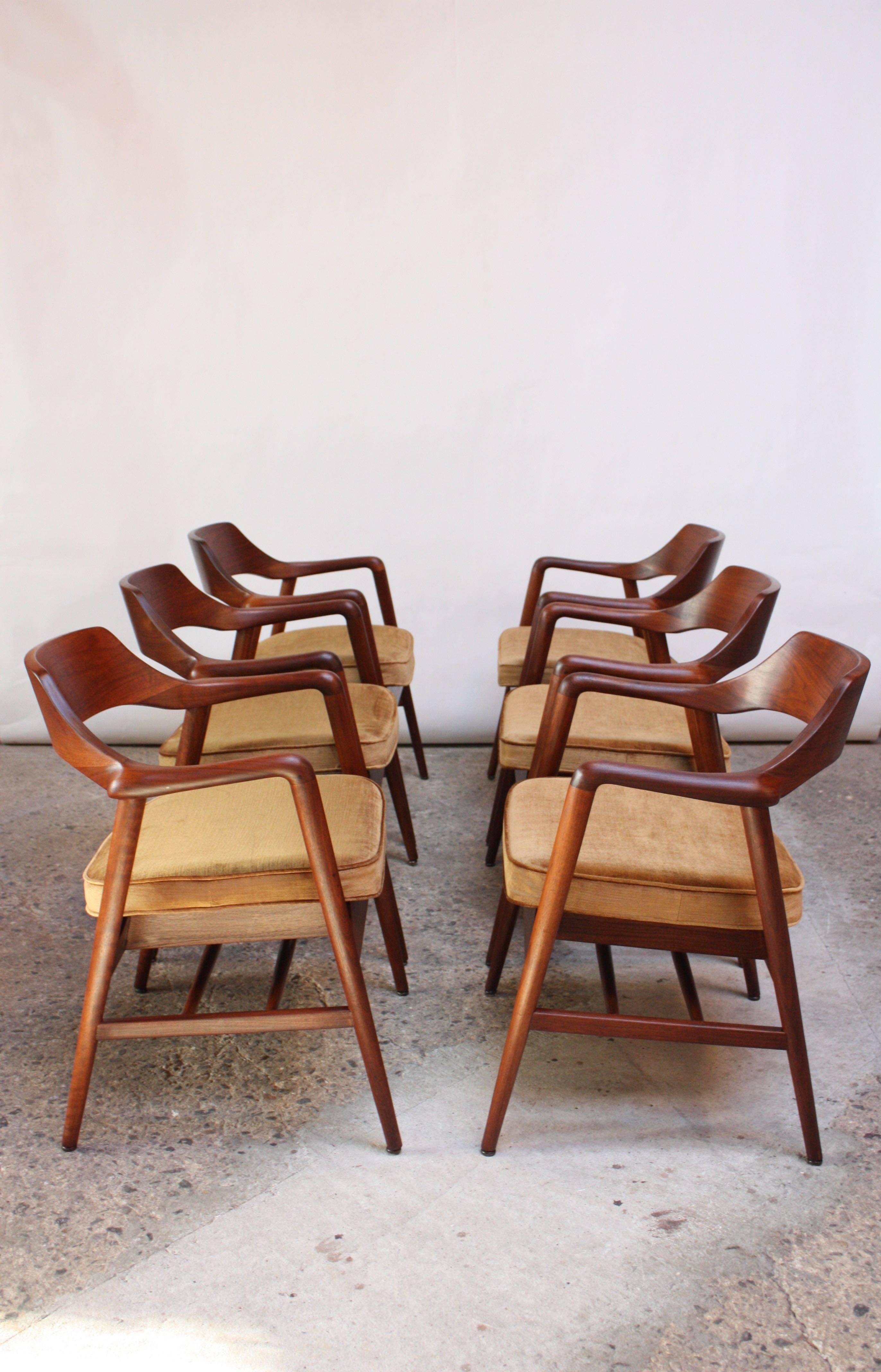 Set of six American modern walnut armchairs manufactured by the W.H. Gunlocke Chair Company of Wayland, New York in the late 1960s. Composed of solid sculpted walnut frames with spindle construction to the underside serving as additional storage or