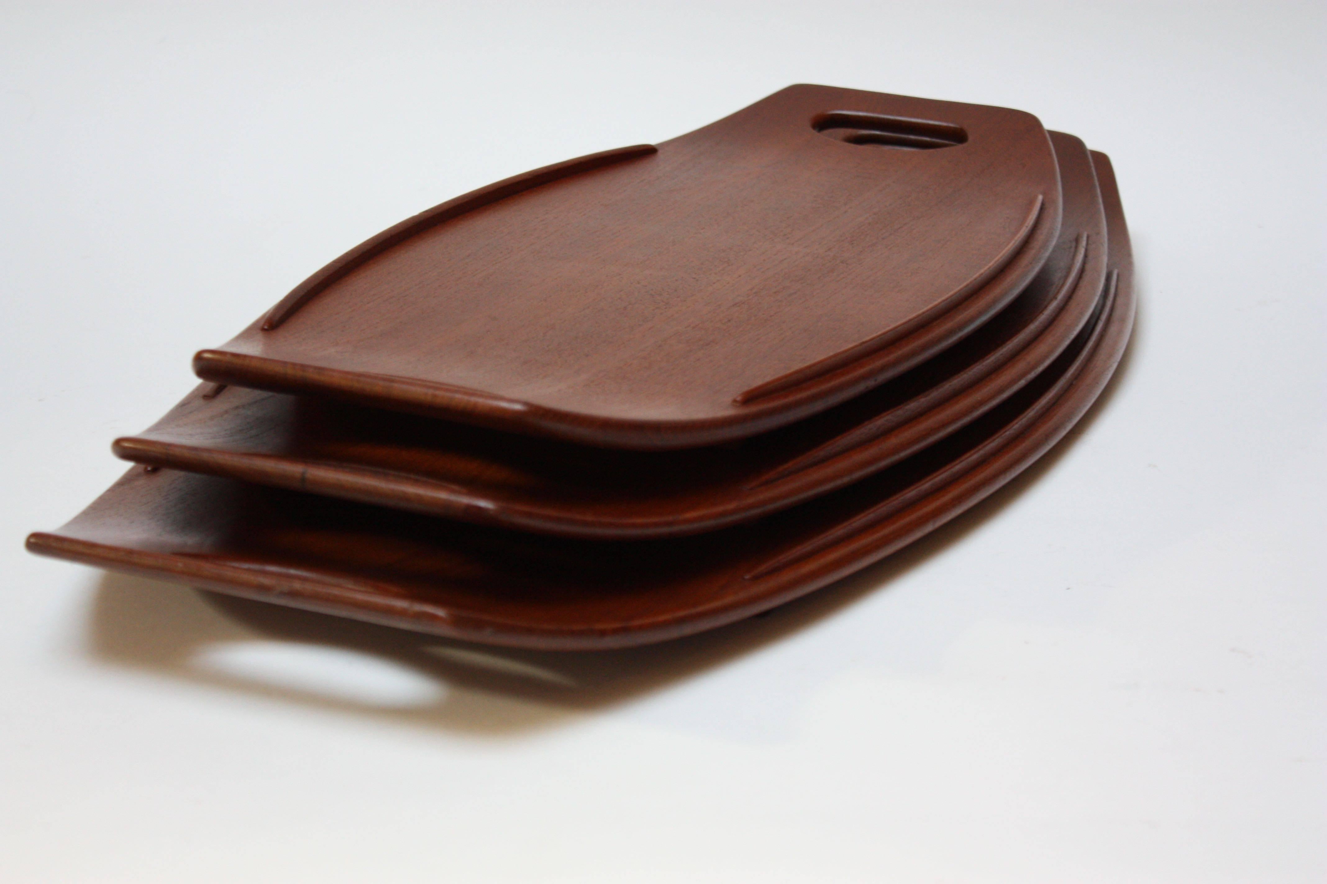 Complete set of three staved teak serving trays by Jens Quistgaard for Dansk. Designed with a slight size disparity (small, medium, and large) to allow the trays to nest together when not in use.
Early examples, as indicated by the stamp to the