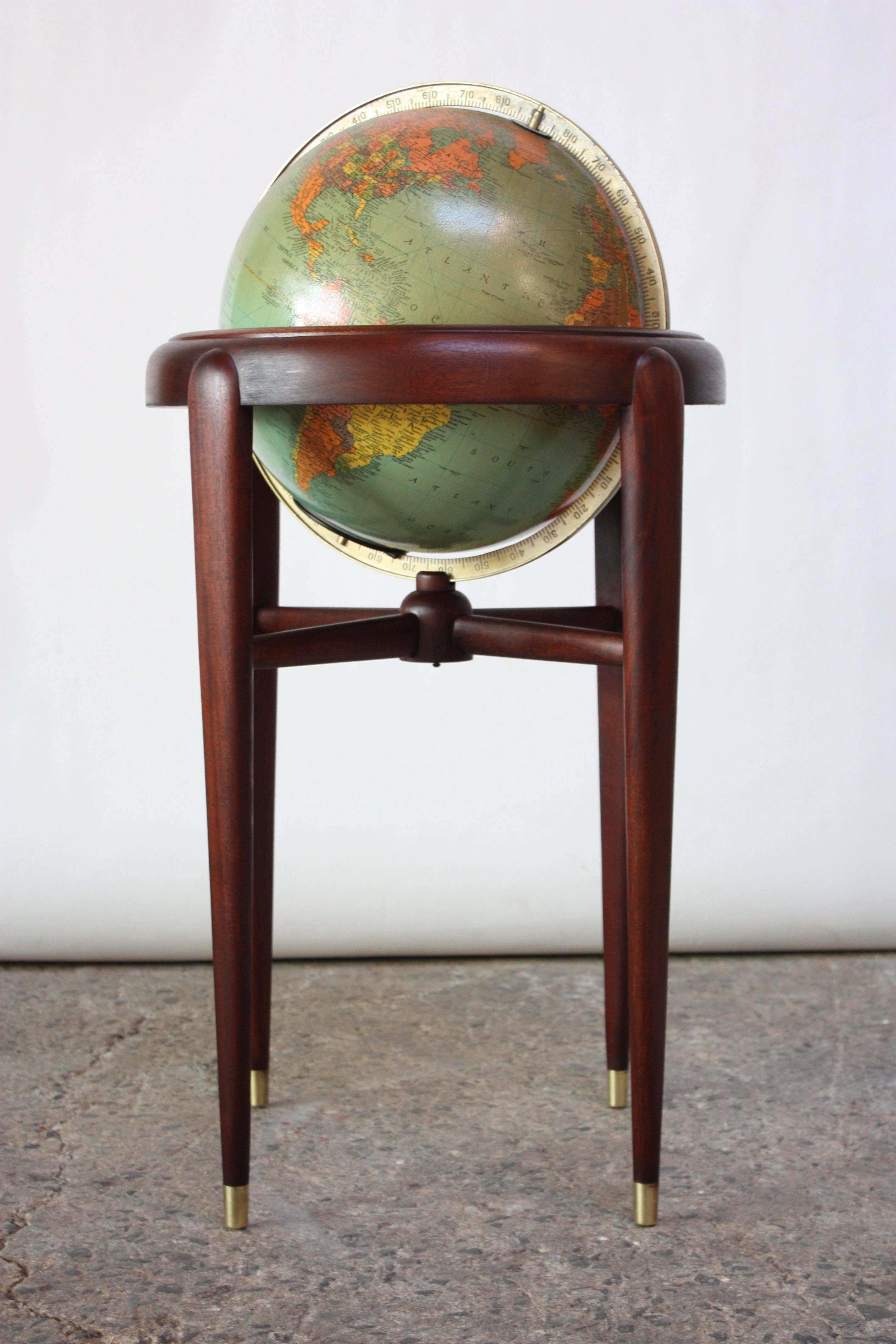1960s Replogle (Chicago, IL) globe on stand composed of paper gores over glass with a cast metal meridian. Base is mahogany with brass feet and features a full 360 degree swivel action. Wear / spots of loss to the globe itself, as pictured; base is