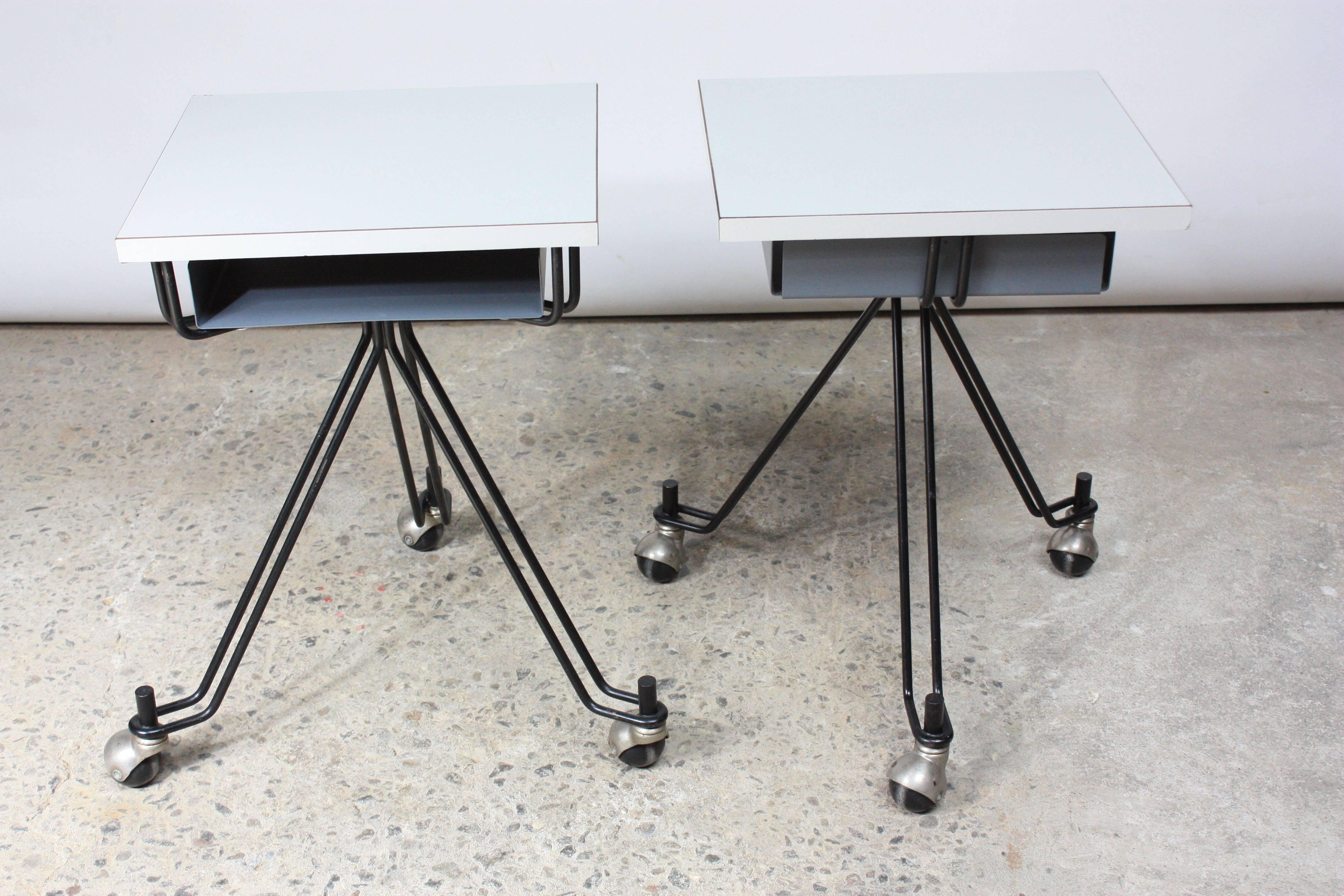 These tables were designed in 1955 by Eliot Noyes for IBM and feature white laminate tops and enameled steel/iron frames. The frames are supported by caster wheels, which allow for easy mobility. 
There is minor loss to the laminate and minimal