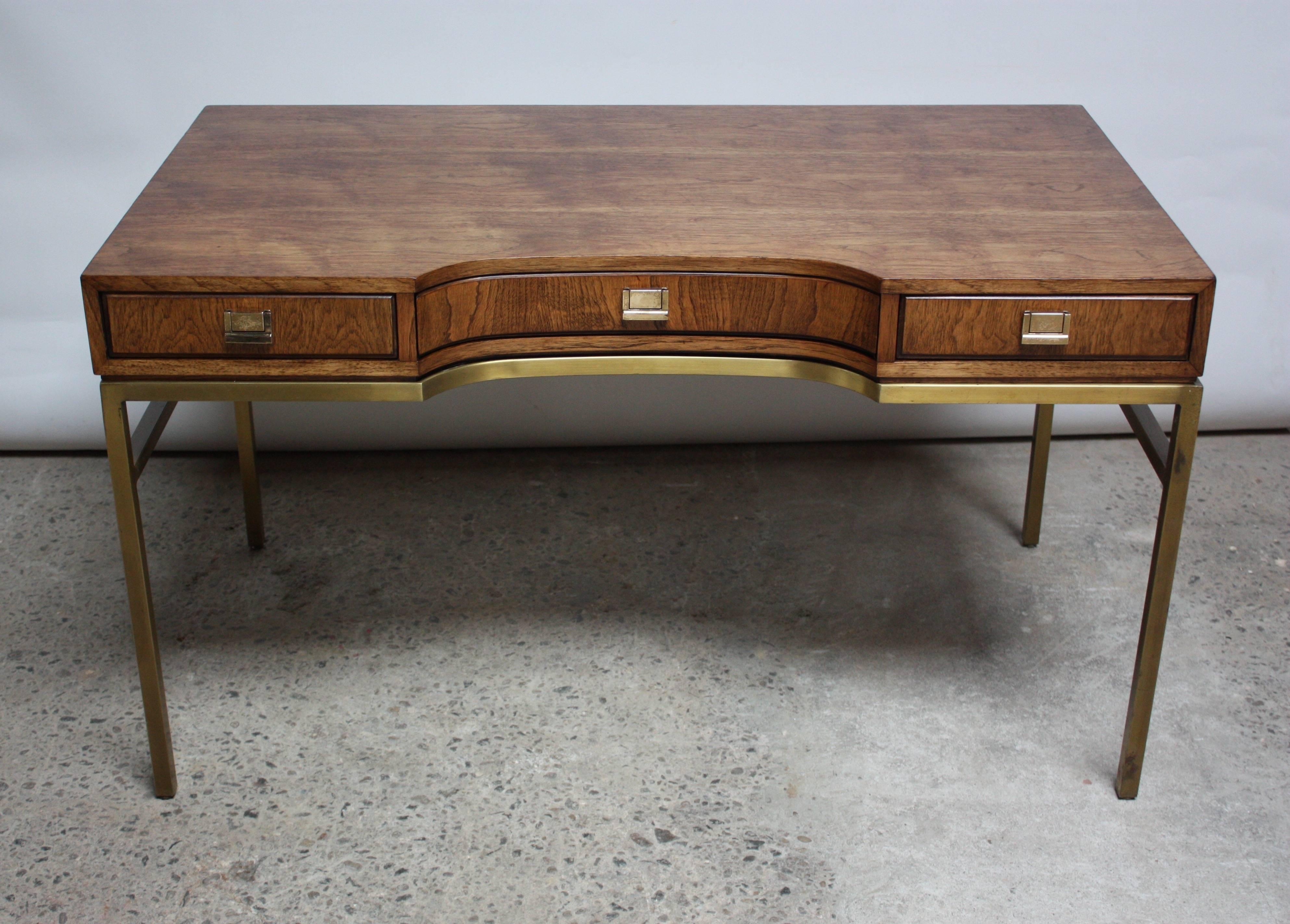 This luxurious desk is comprised of an ash surface with brass hardware and a polished brass base. There are three drawers for storage as well as built in adjustable glides as feet for the base.